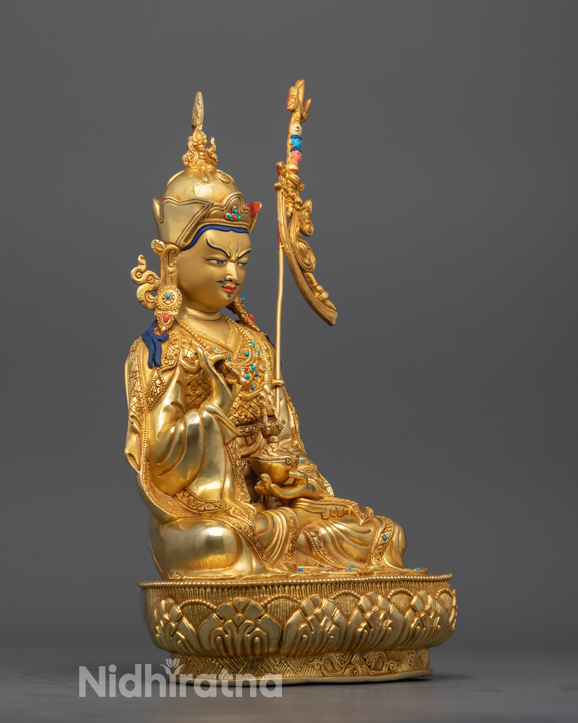 Side angle of hand-carved Padmasambhava statue holding vajra