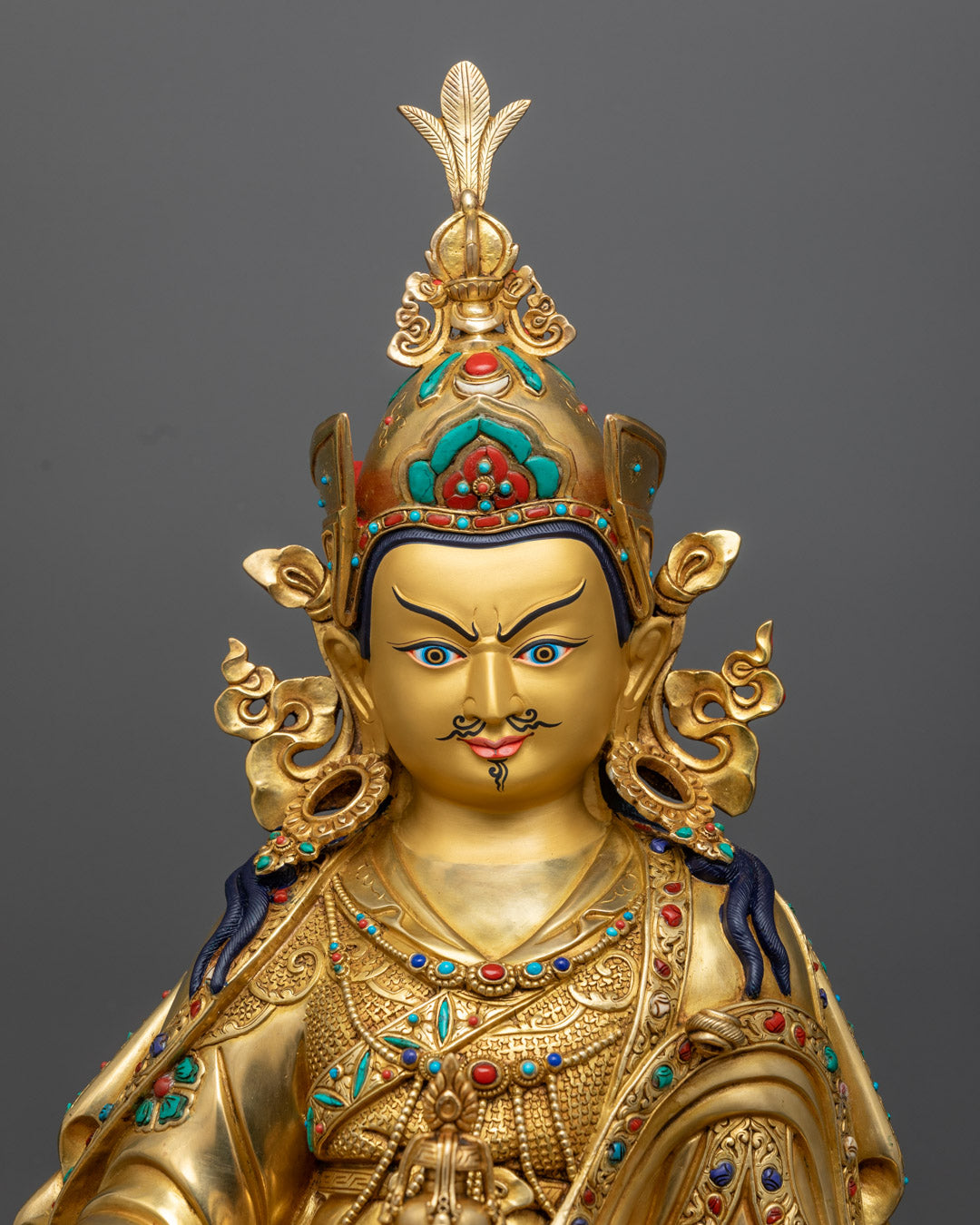 Guru Rinpoche’s serene face and regal crown, highlighting the intricate craftsmanship and spiritual expression of the statue