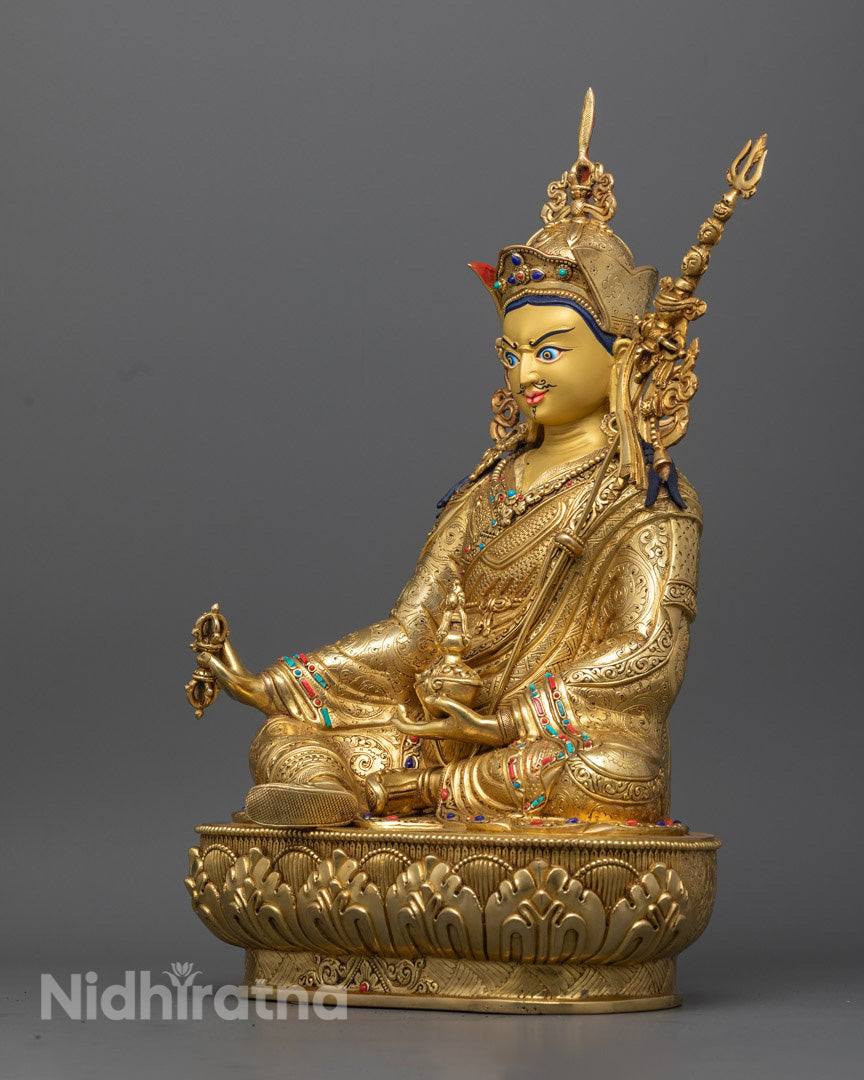 Guru Rinpoche statue with radiant gold finish, semi-precious stone inlays, and powerful symbolism of compassion and wisdom.