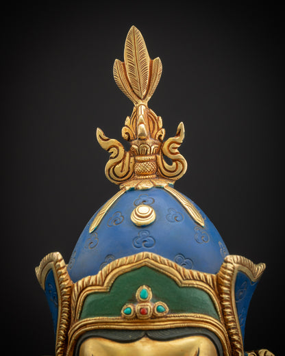 Close-up of Guru Rinpoche lotus hat with vulture feather finial, detailed gold and copper work.