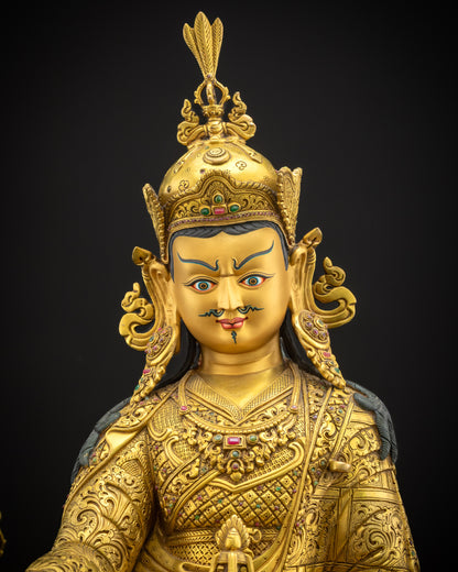 Close-up of Guru Rinpoche sculpture showing intricate craftsmanship, gold-gilded details, and hand-carved kasaya robes