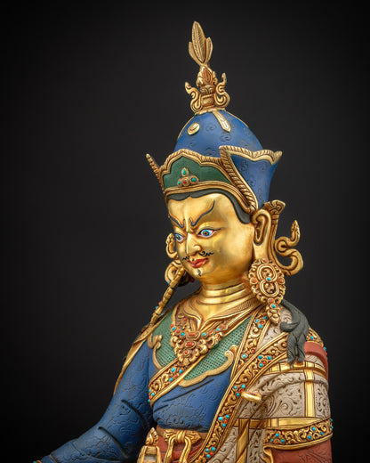 Side close-up of Guru Rinpoche statue showing robe, ornaments, and intricate gold patterns.