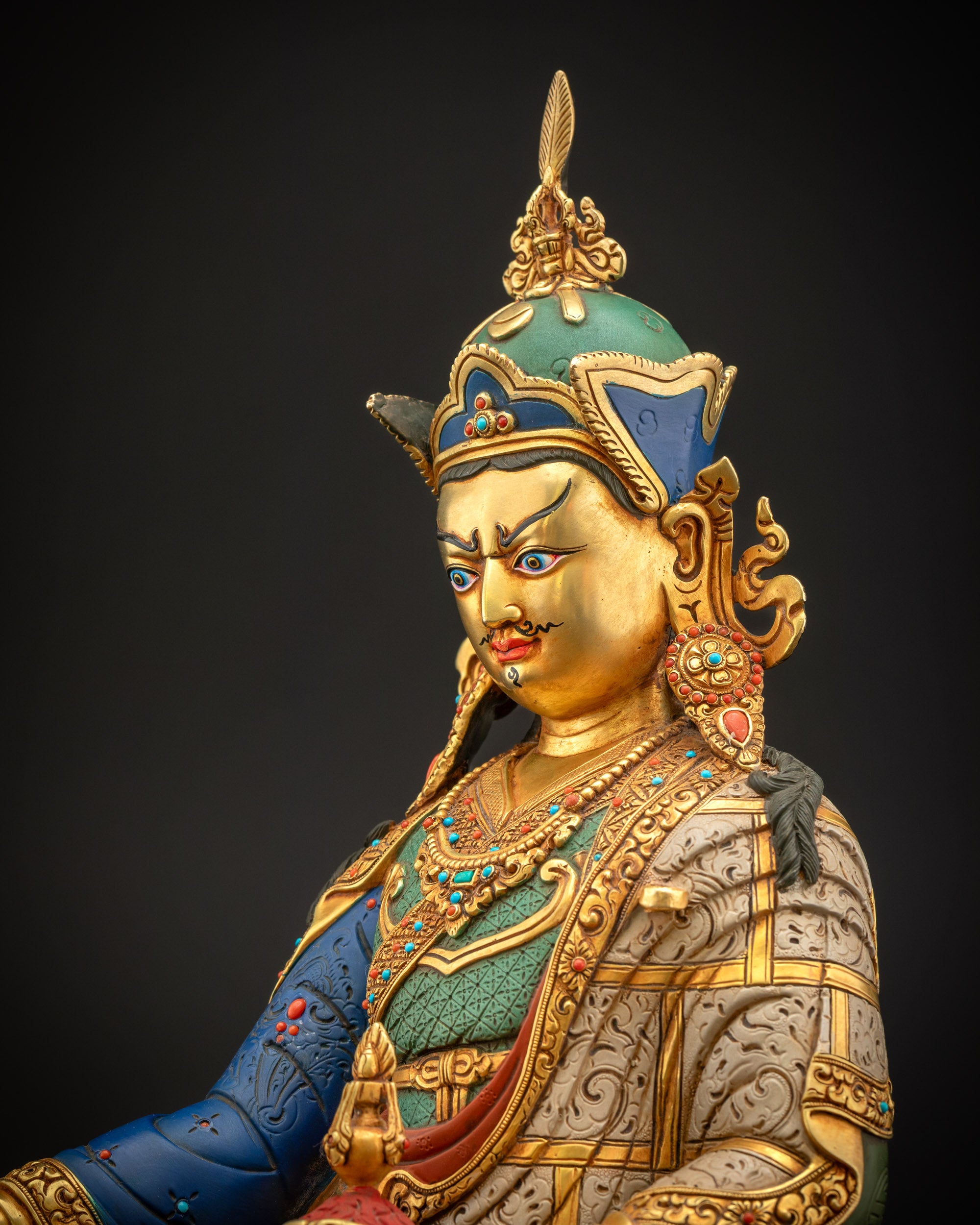 Side close-up of Guru Rinpoche statue showing Tripitaka-style attire and khatvanga staff for meditation altar