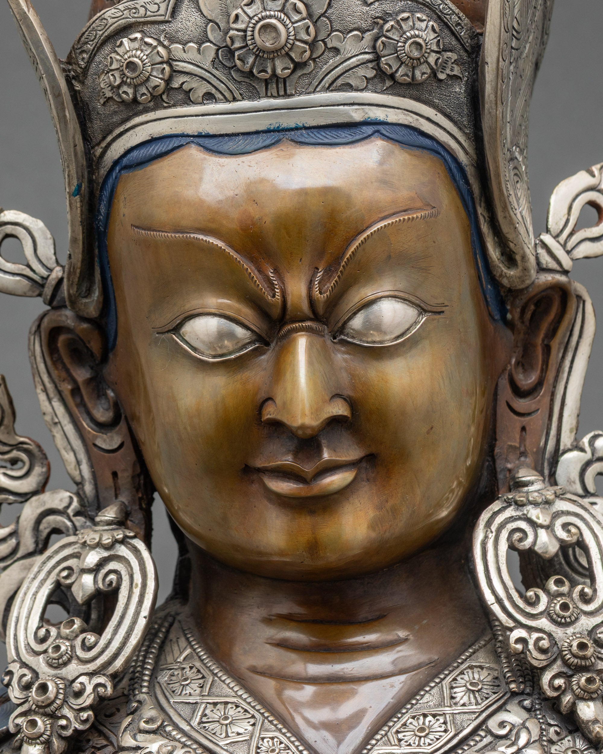 Guru Rinpoche face close-up, hand-painted serene expression, oxidized copper statue Nepal
