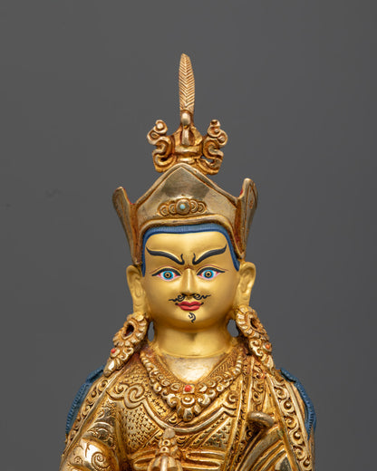 Guru Rinpoche's face, showing fine gold gilding, ornate crown, and hand-painted details with semi-precious stone inlays