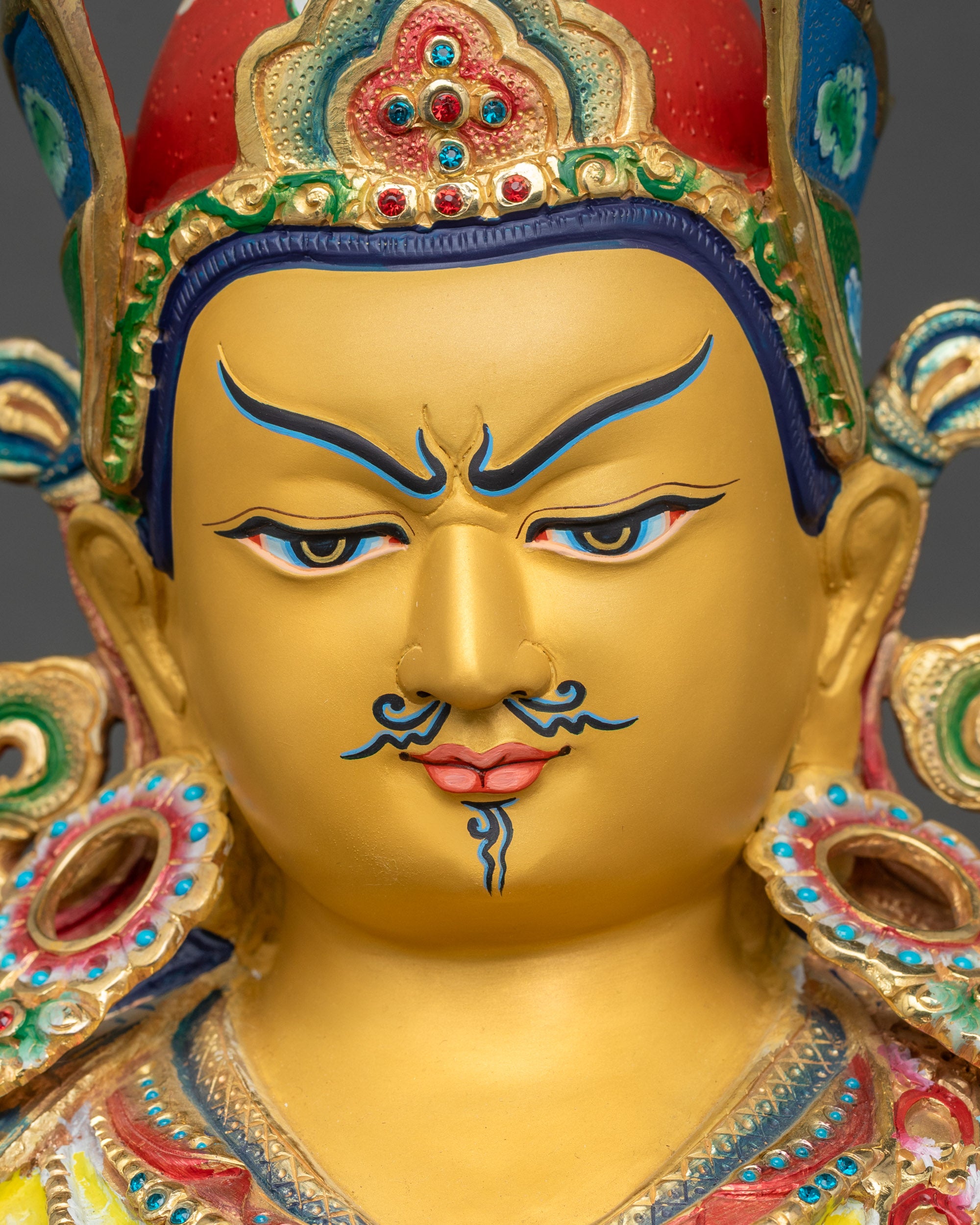 Guru Rinpoche statue detailed close up of face with gold-painted features
