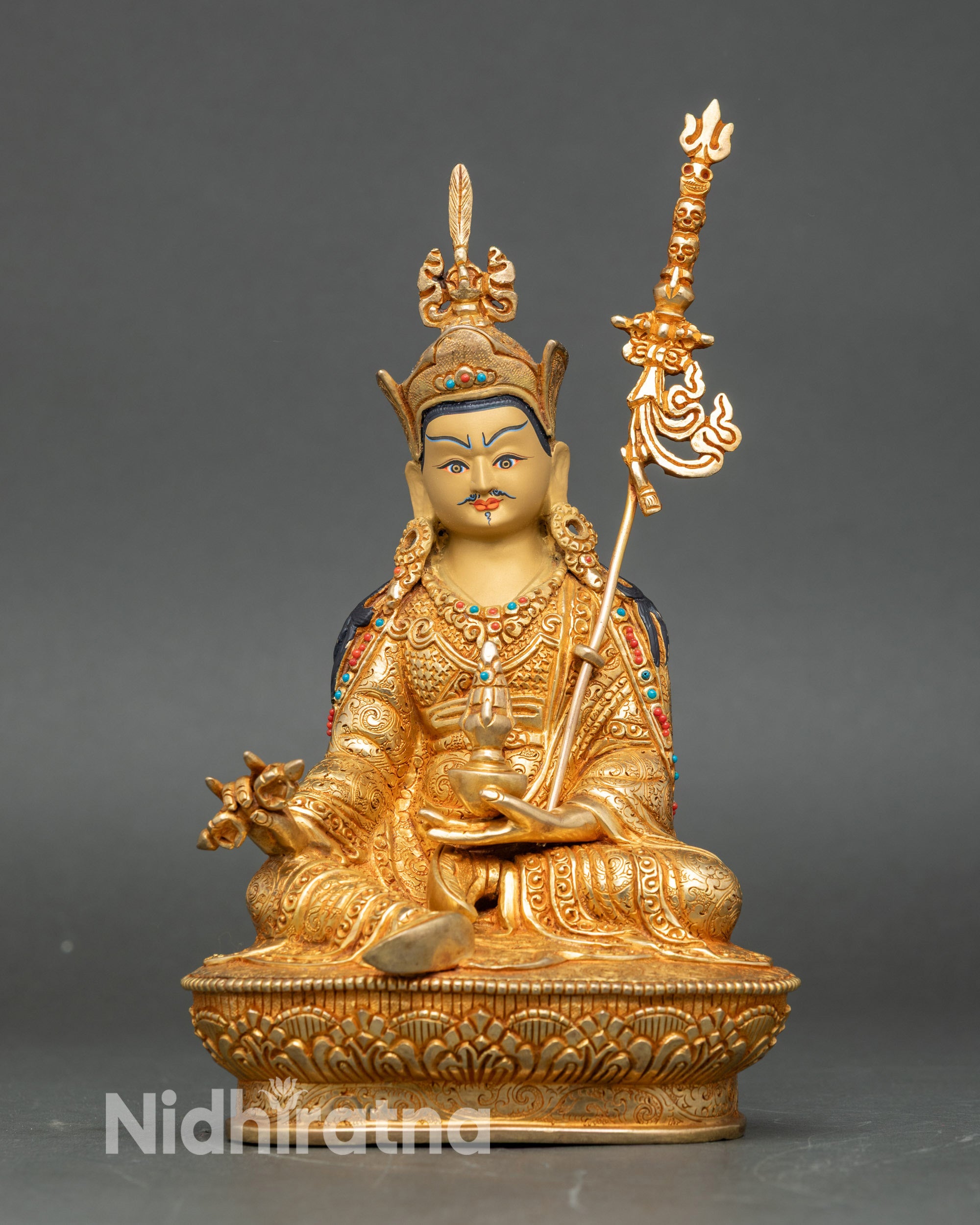 Handcrafted Guru Rinpoche statue in copper with 24K gold gilding, seated with vajra and skull cup, traditional Nepalese Buddhist icon.