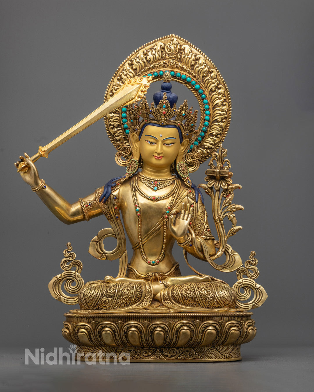Handmade gold Manjushree Buddha statue with sword and turquoise-decorated halo, symbolizing wisdom and enlightenment, seated on a lotus base.