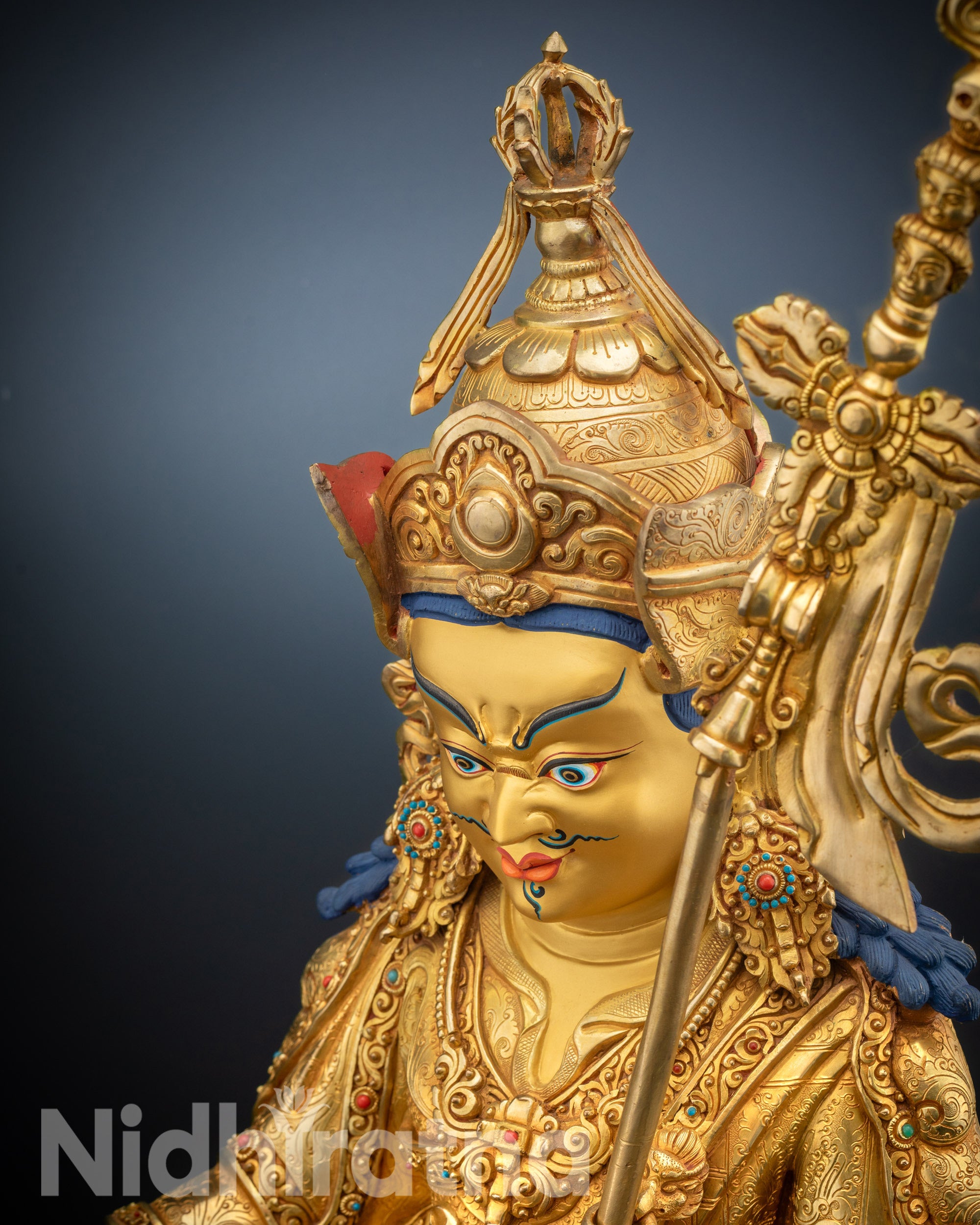 High-angle shot of Guru Rinpoche statue with gold fire-gilding and lotus pedestal