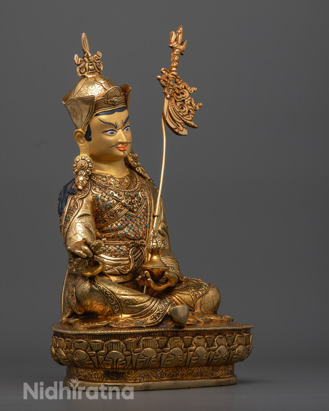 Intricately carved Guru Rinpoche statue adorned with semi-precious stones symbolizing protection and spiritual guidance