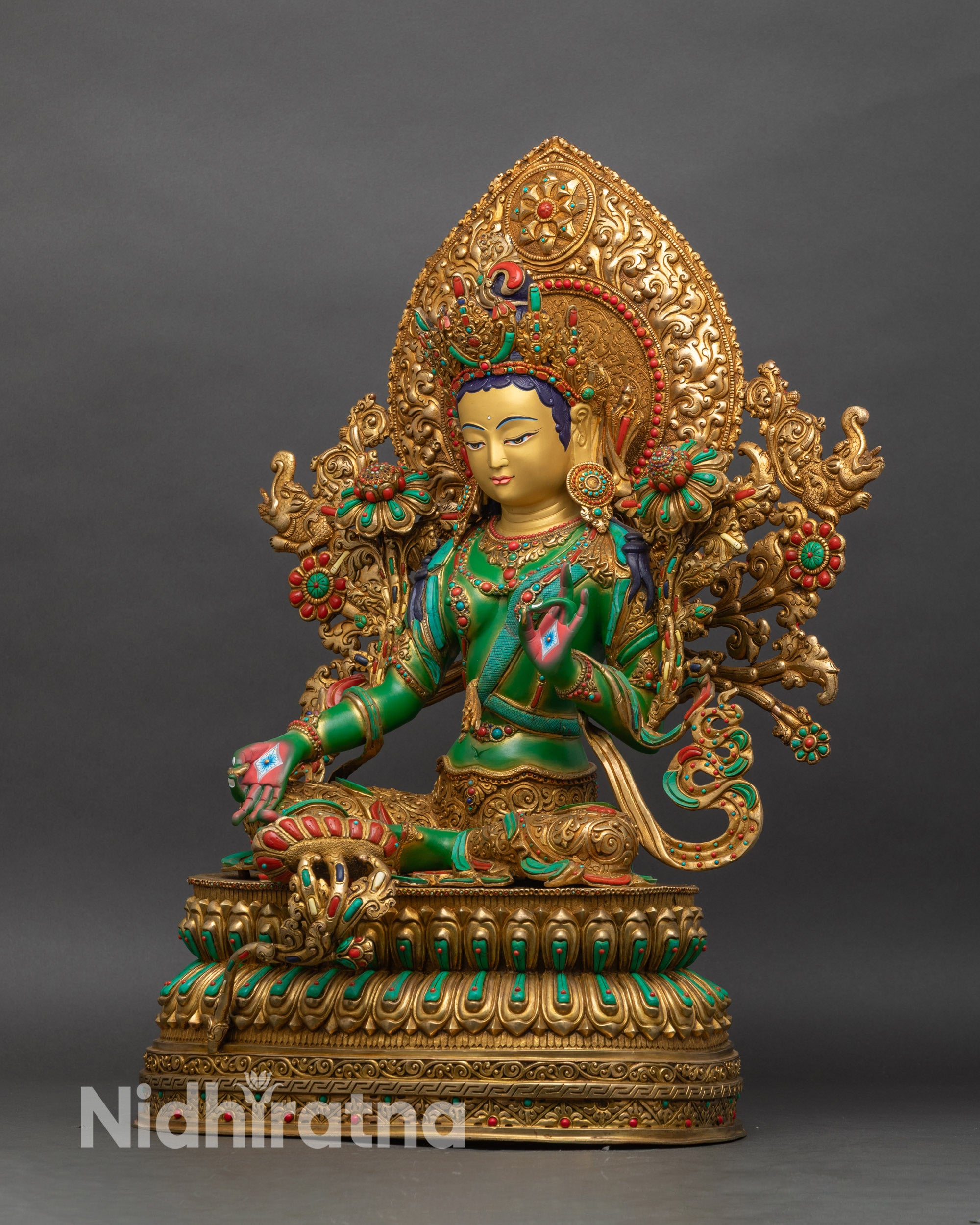 Left profile of Green Tara Droljang statue, gold-gilded robes, ornate floral halo