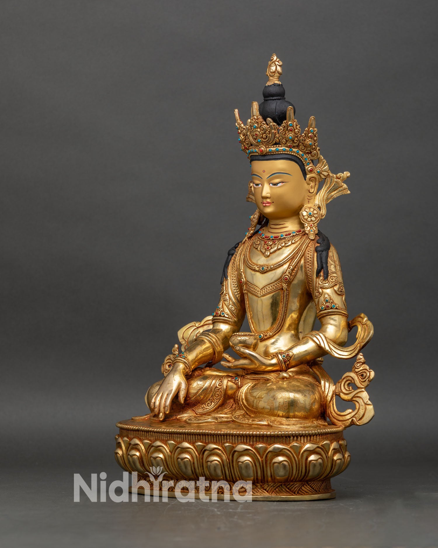 Left profile of crowned Shakyamuni Buddha statue in gold-gilded copper with lotus base