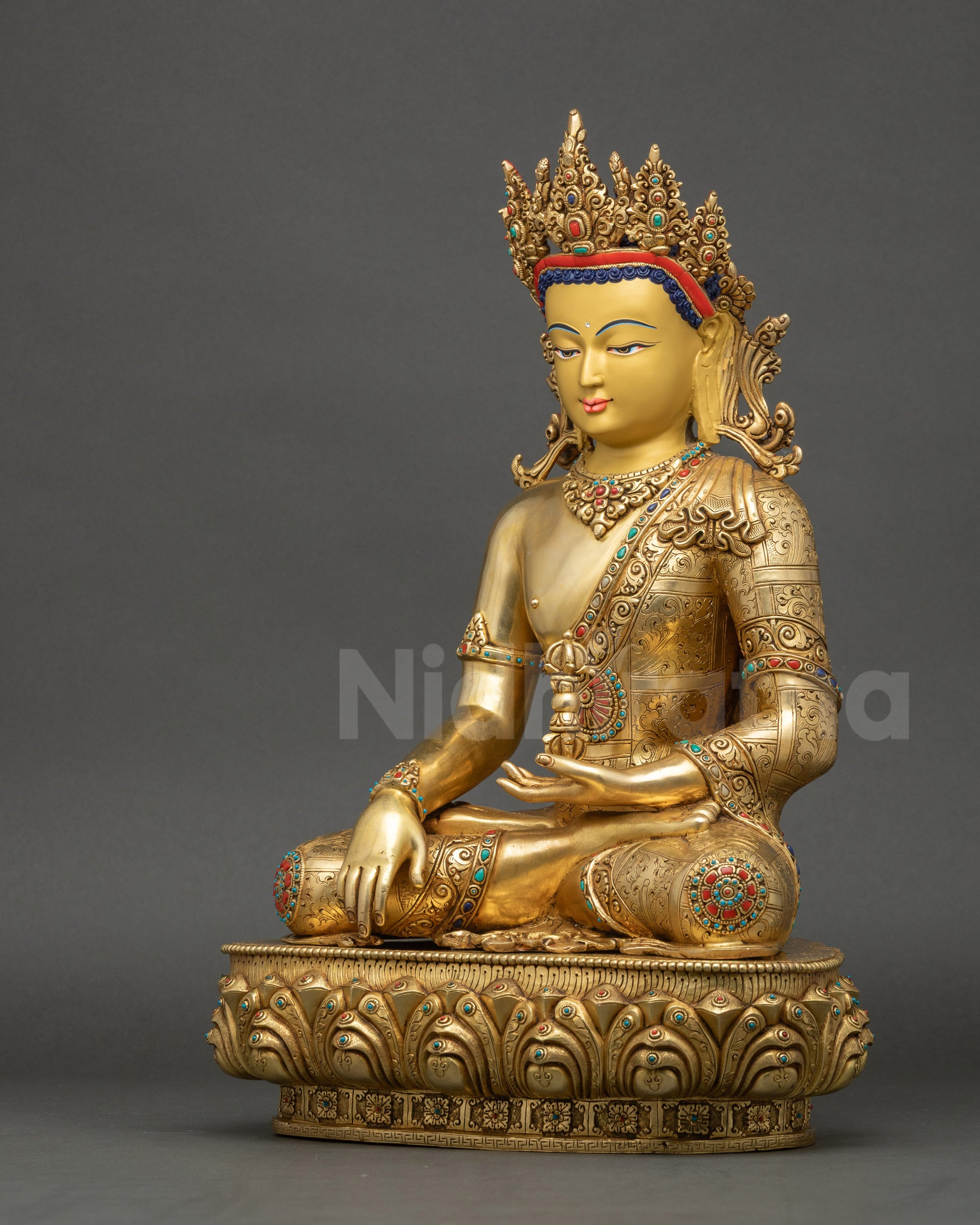 Left side of Mitrugpa Buddha statue highlighting meditation posture, Vajra, and gold-gilded details.