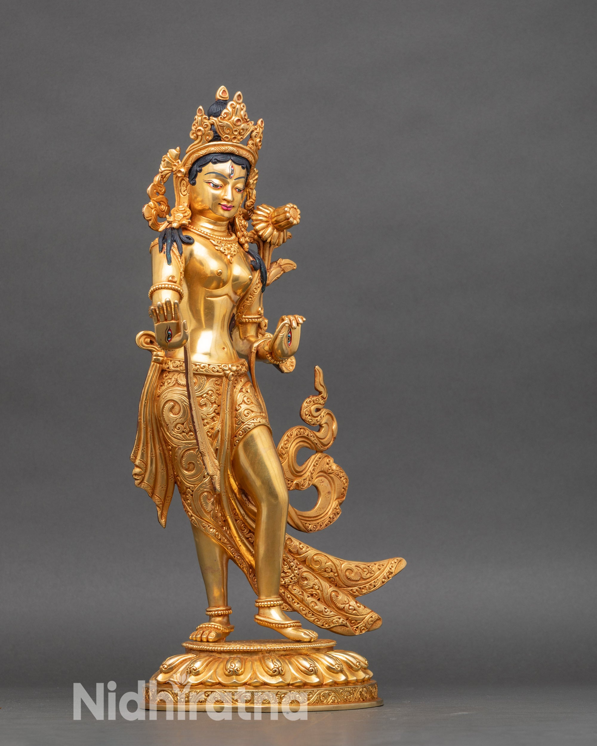 Left side of White Tara sculpture, holding utpala lotus, intricate garments