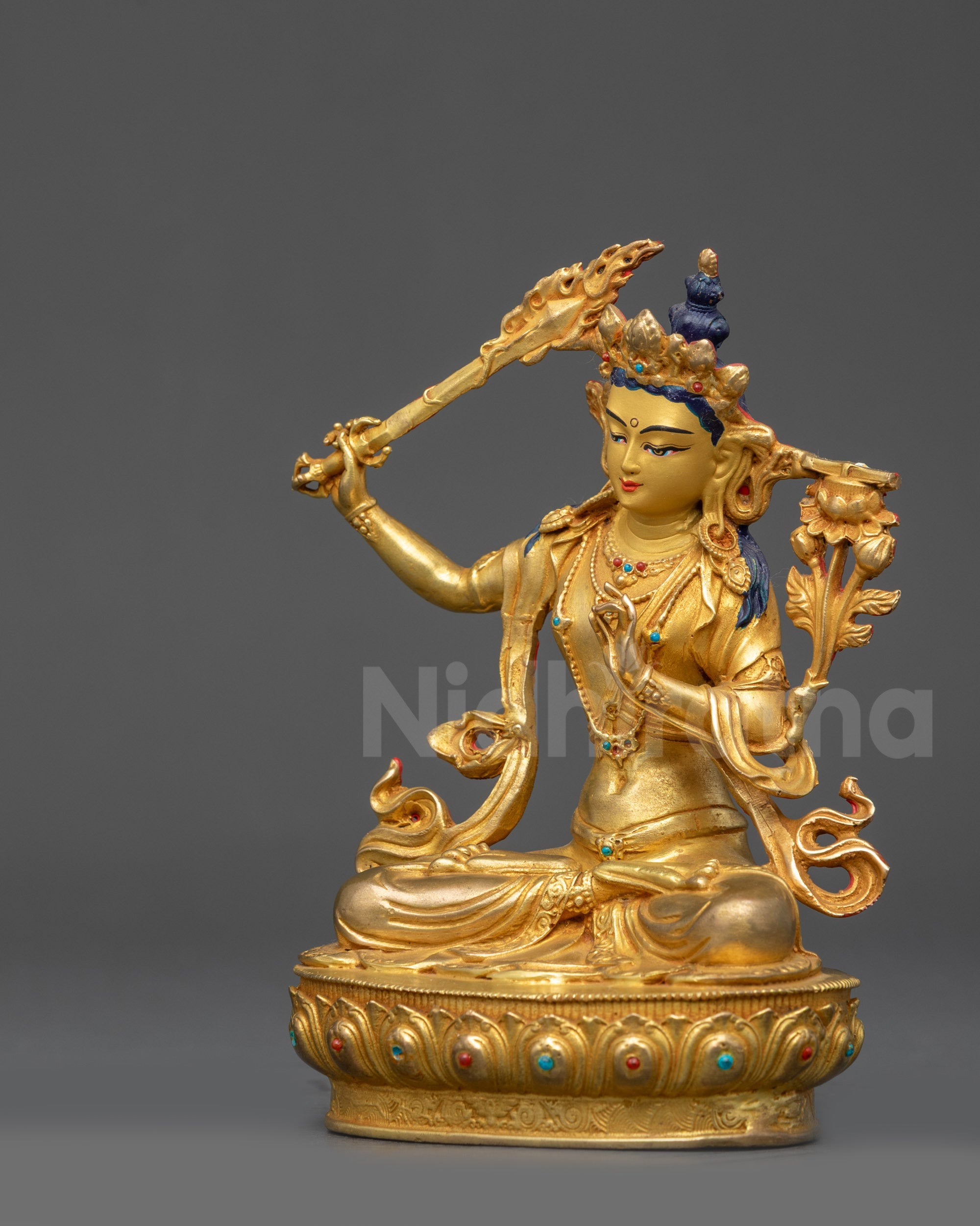 Left side view Manjushri Statue with intricate swirling robes and gold fire-gilded base
