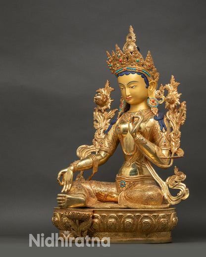 Left side view of Green Tara sculpture holding utpala flower in lotus pose