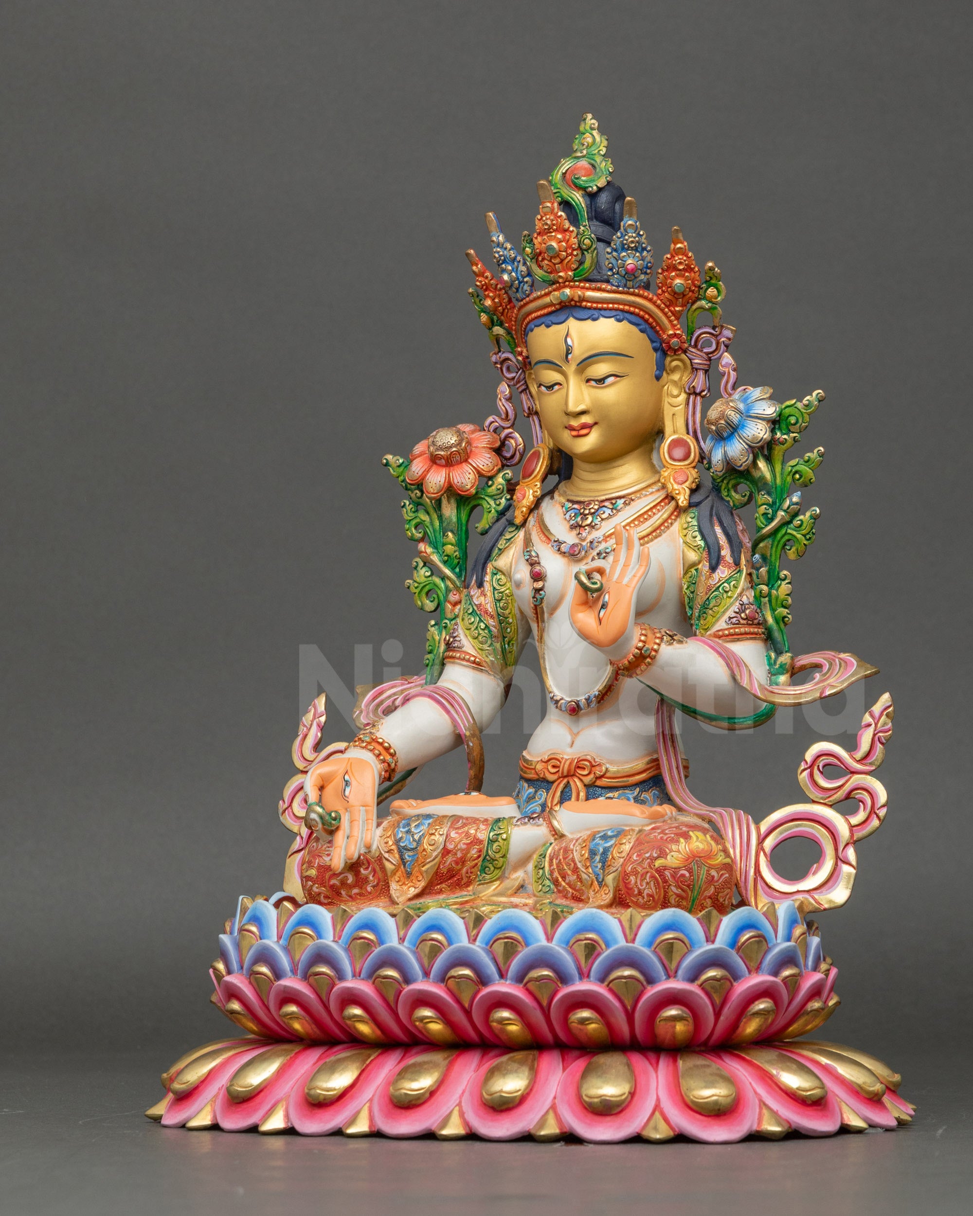 Left side view of White Tara statue with intricate floral robes and lotus seat