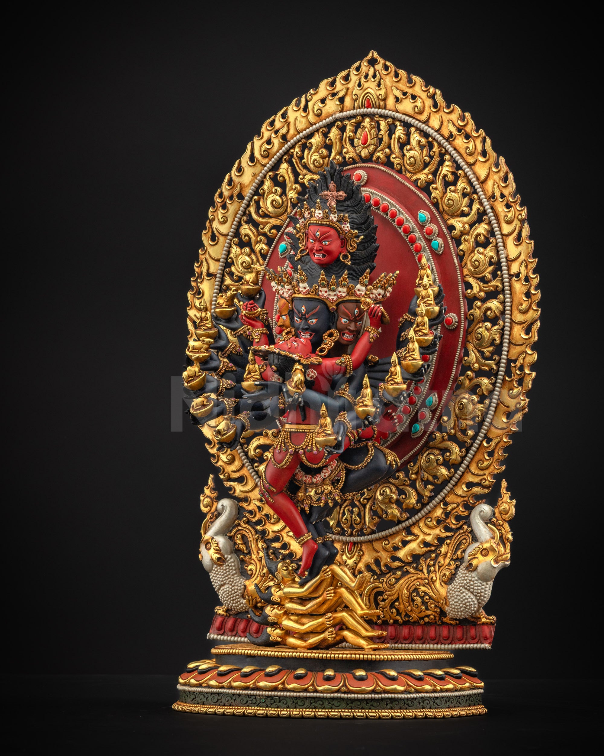 Left side view with left arms holding skull cups with animals