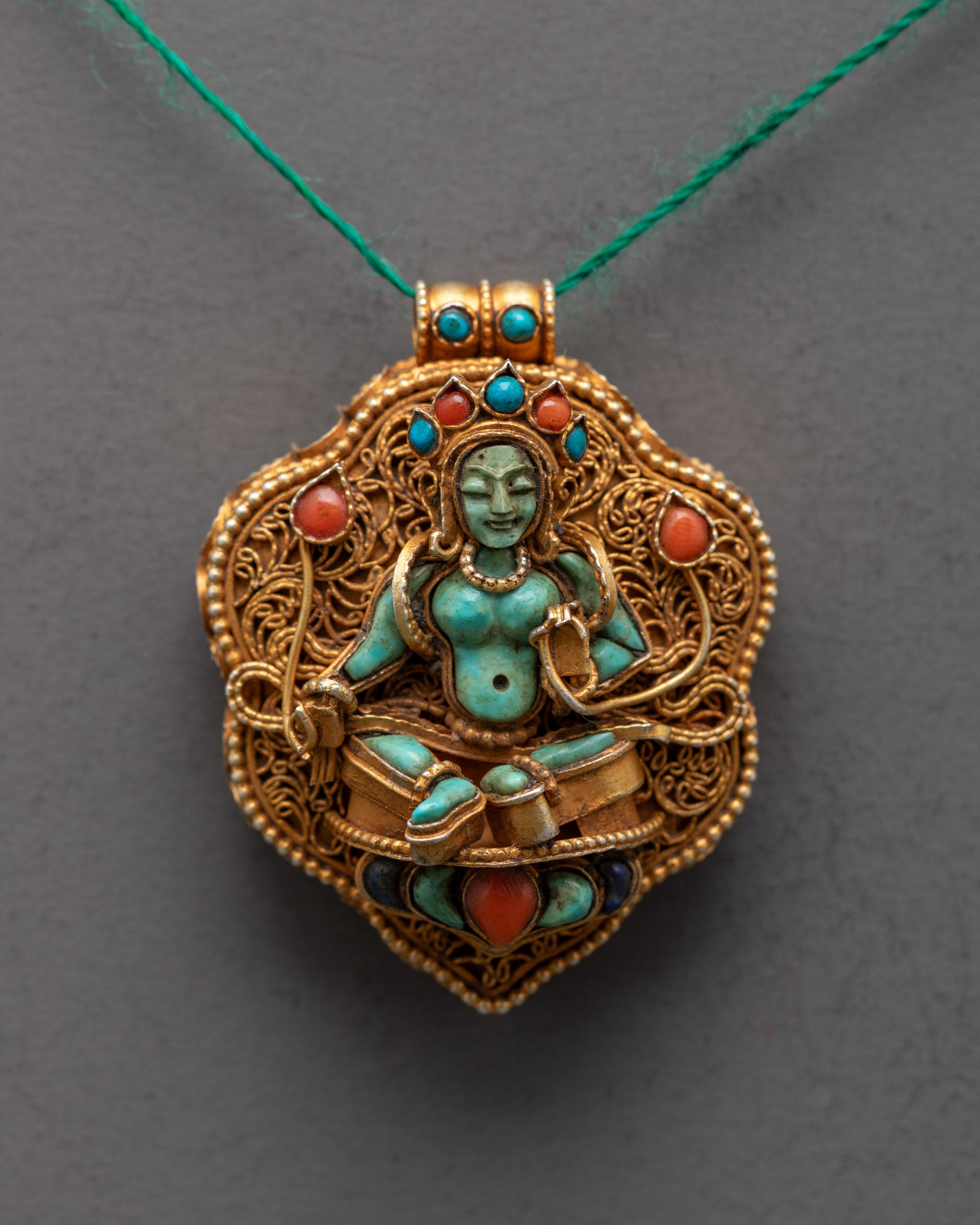 Close-up of intricate gold filigree and semi-precious stones on Green Tara locket pendant