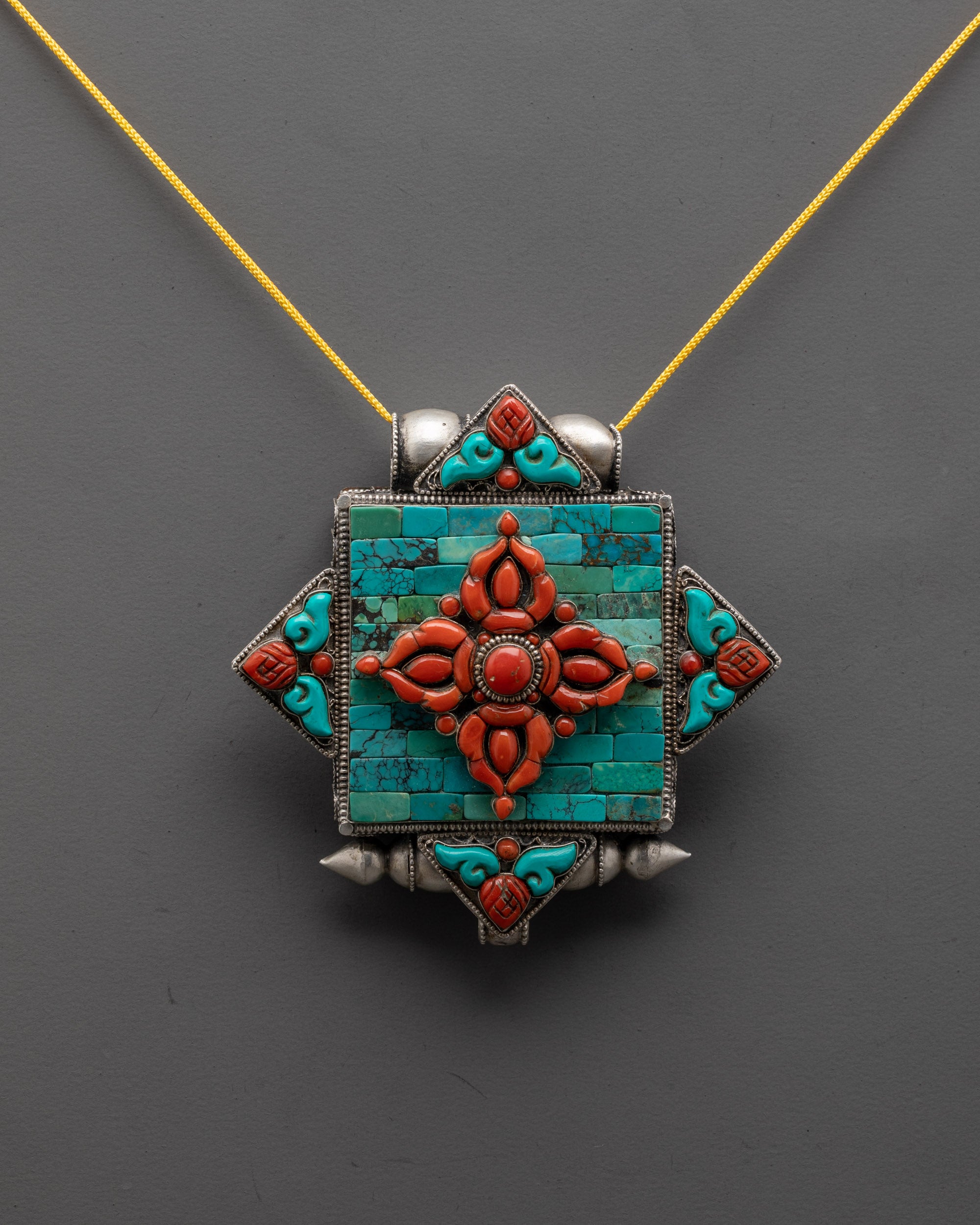front view of Bishwo Vajra locket with coral vajra and turquoise on silver body