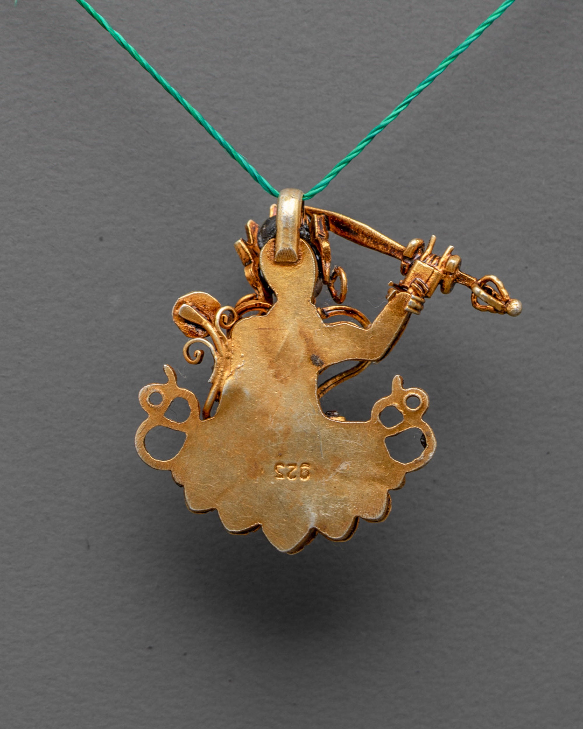 Back view of Tibetan Manjushri amulet showing detailed artisan carvings and gold finish