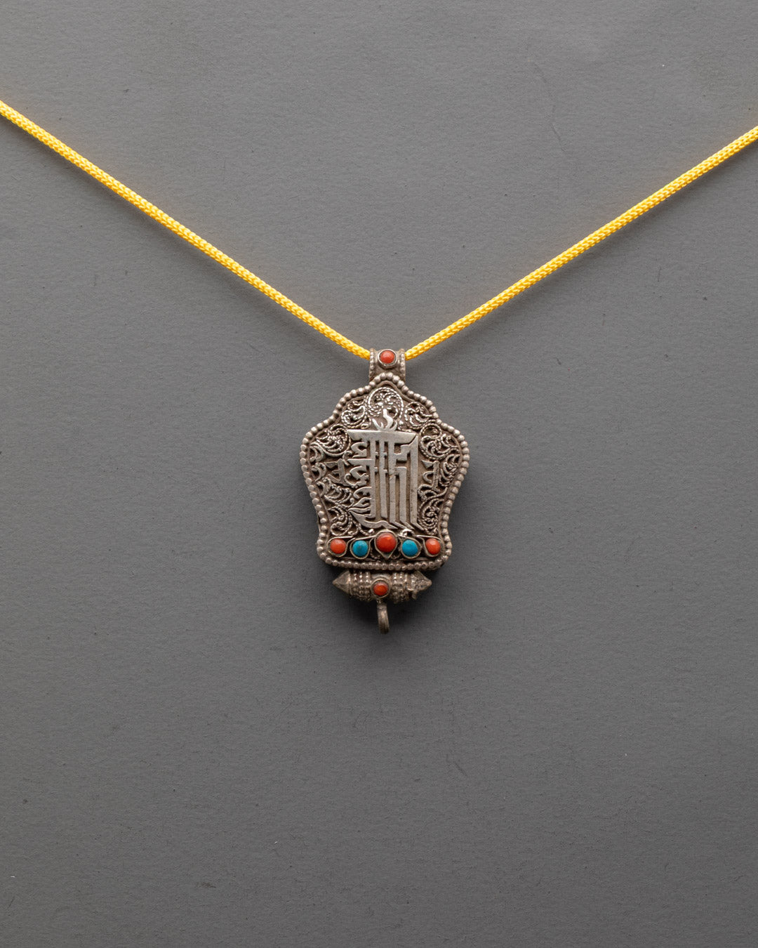Front view of Kalachakra Mantra Amulet Pendant with silver filigree and turquoise, coral stones
