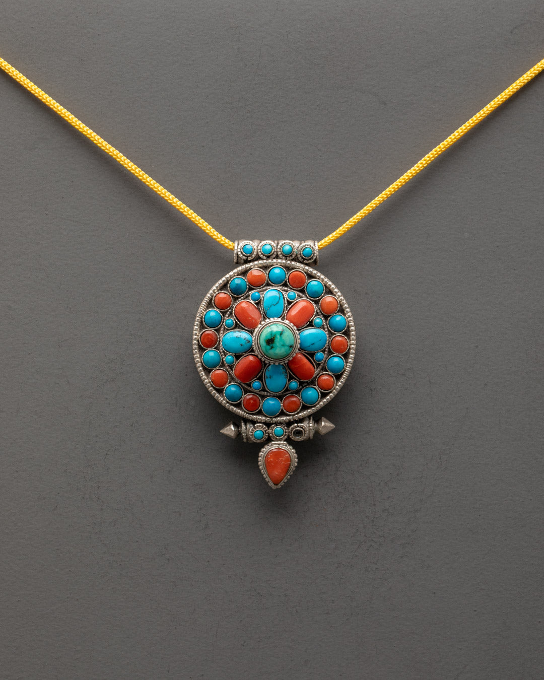 Front view of Tibetan Buddhist Pendant with shining silver body and semi-precious stones
