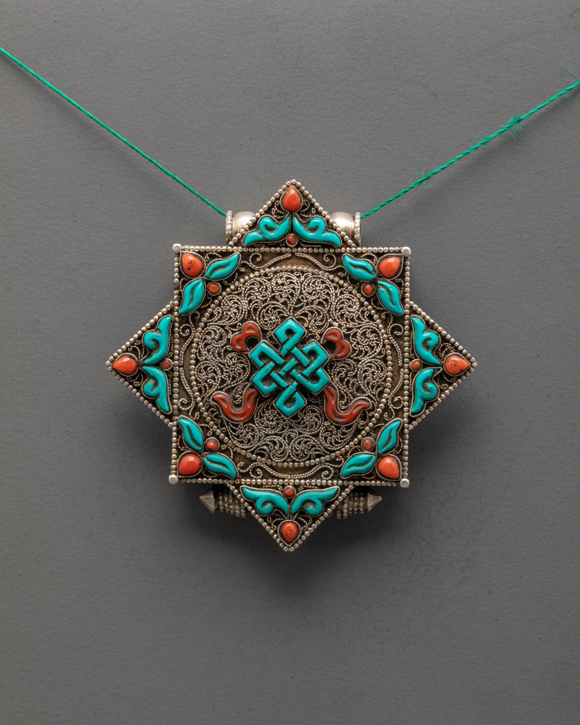 Front view of Elegant Endless Knot Locket with silver body and turquoise coral stones