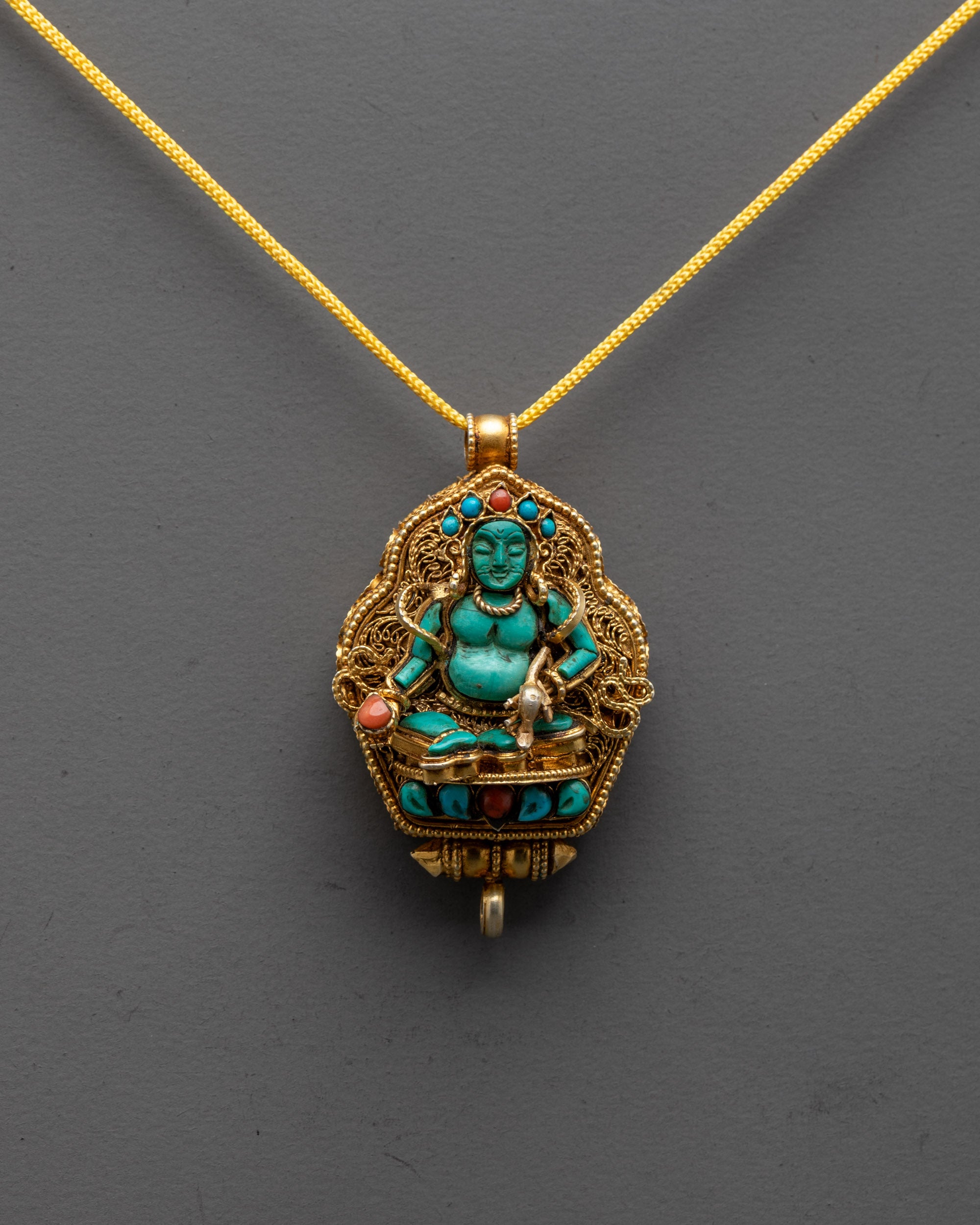 front view of gold-plated Dzambhala locket pendant with turquoise figure and filigree design
