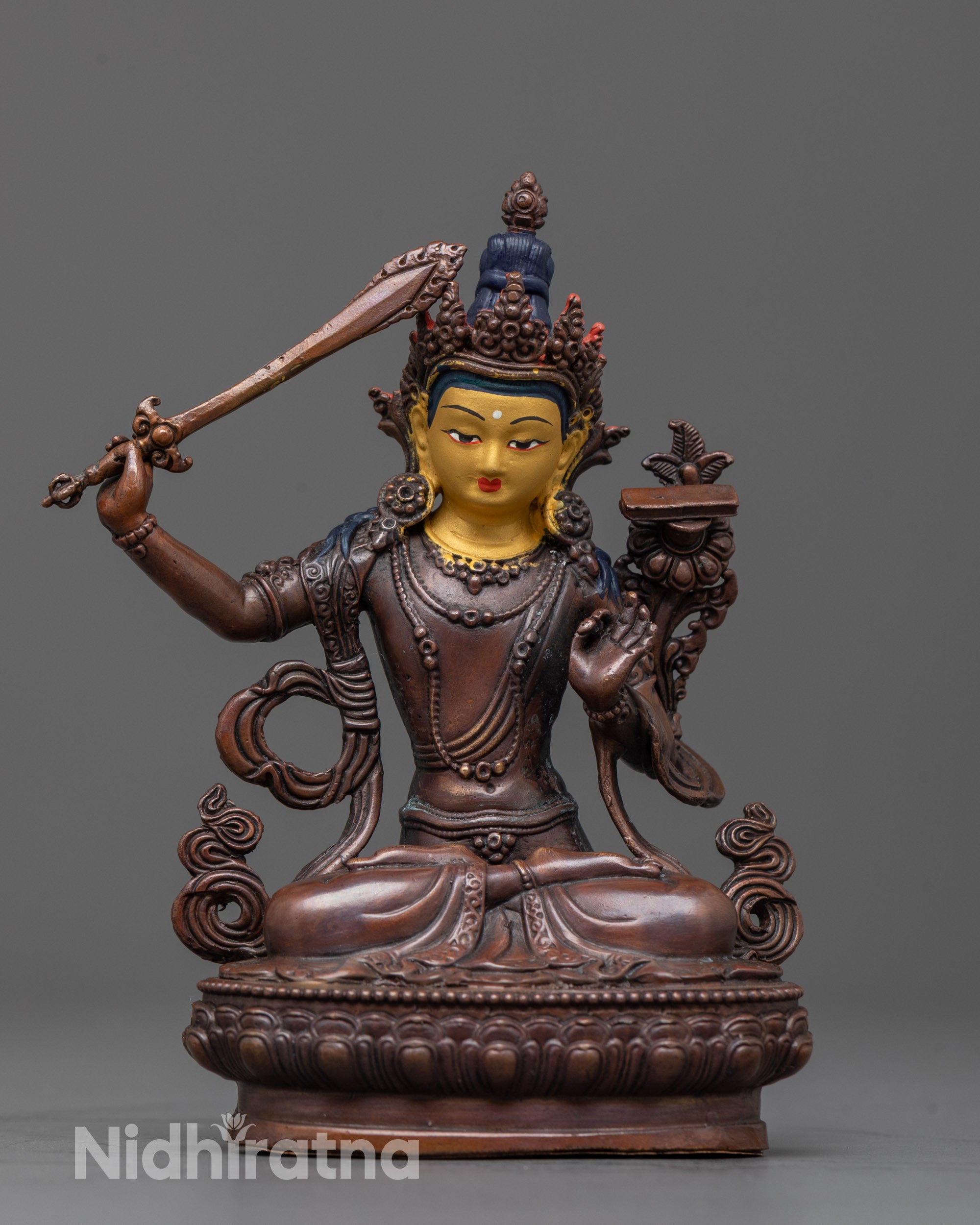 front view of machine-crafted manjushri statue with gold face and oxidized copper body