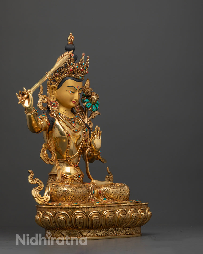 Manjushri Buddha statue, showcasing the flowing details of the robe, the precision of gold gilding, and the elegant arrangement of semi-precious stones that enhance the statue’s divine and majestic presence.