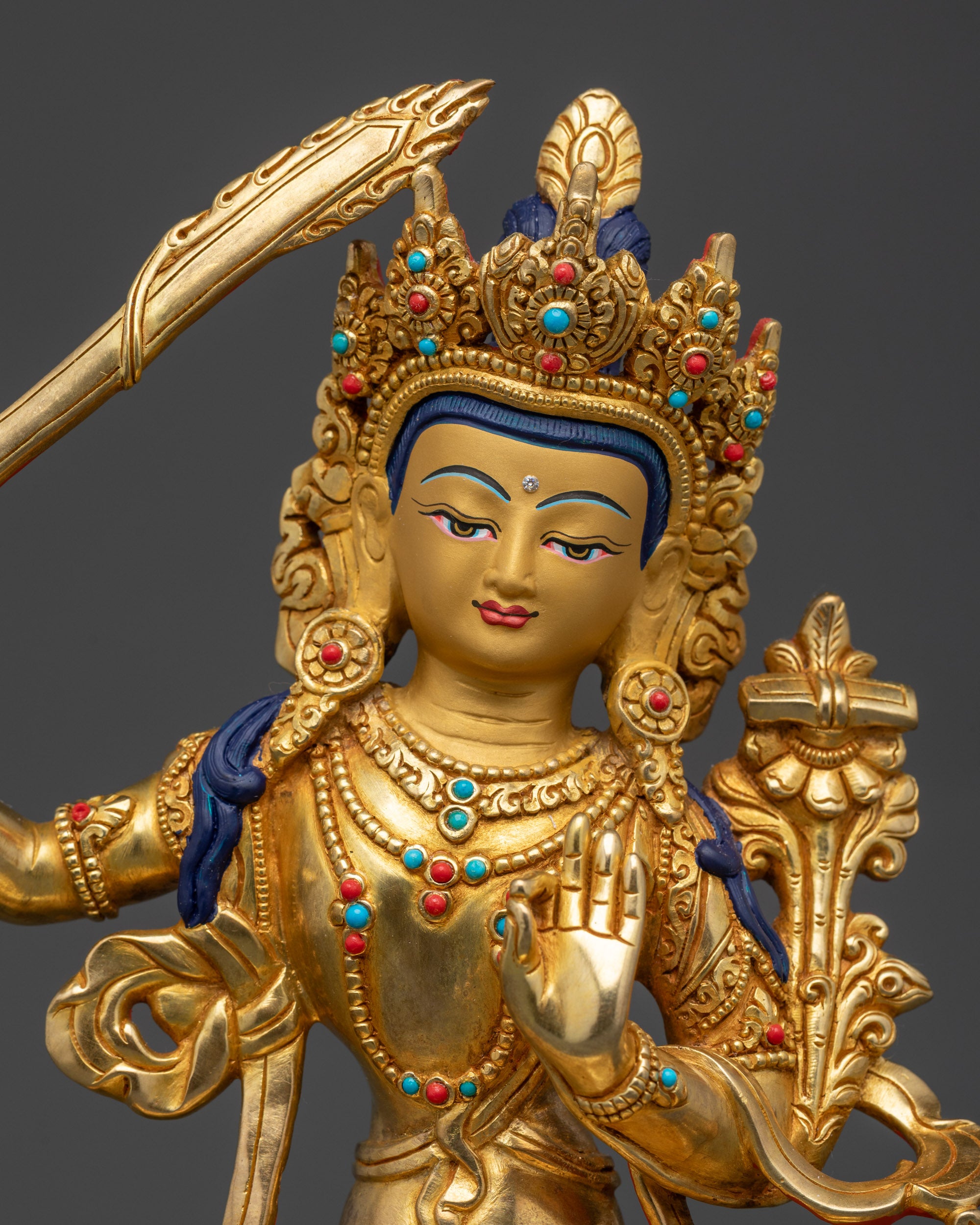 Manjushri Statue close up showing serene gold-gilded face and intricate robes