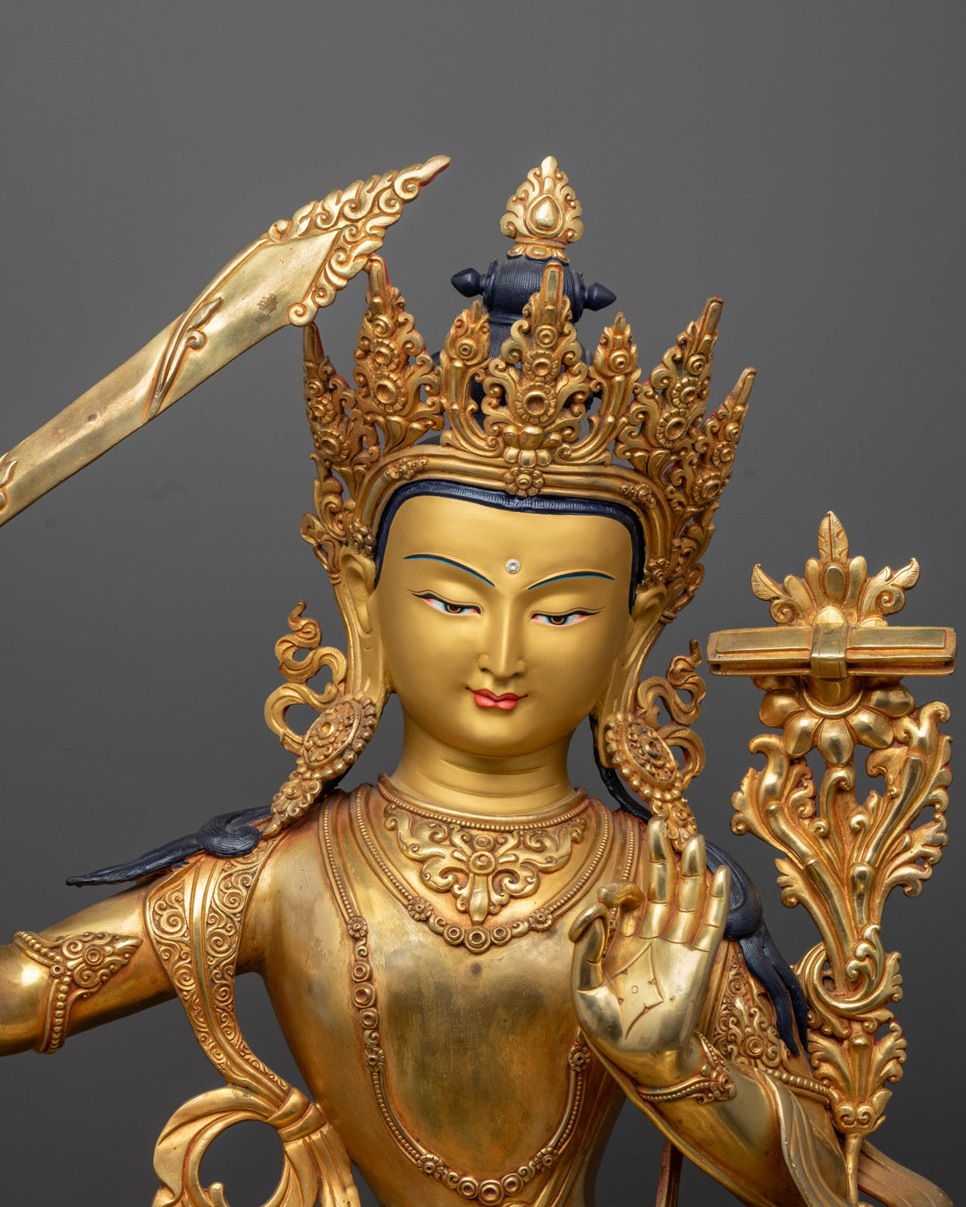 Manjushri’s serene gold-gilded face and flaming double-edged sword symbolizing wisdom cutting through ignorance.