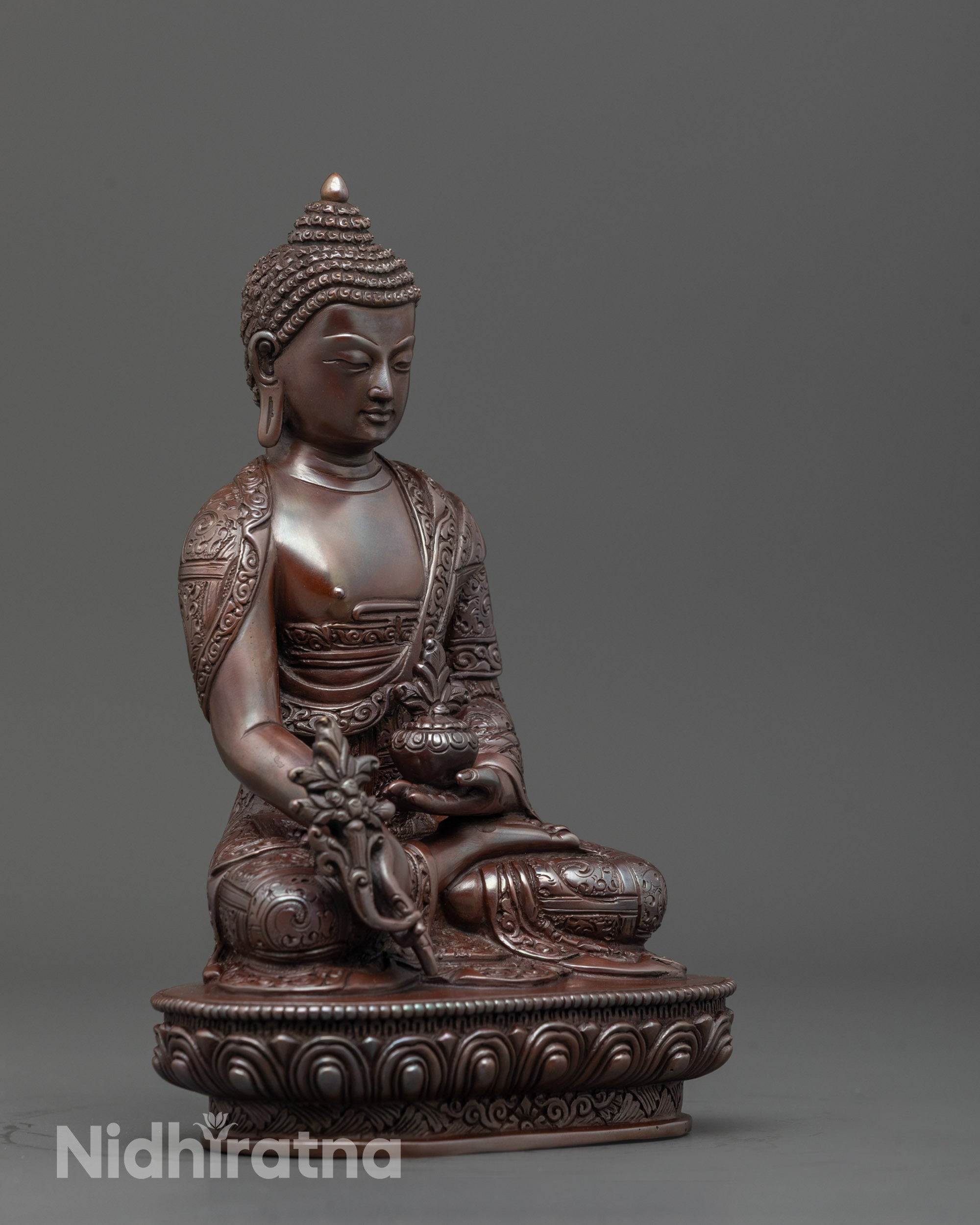 Side angle of Tibetan Medicine Buddha holding monk’s bowl with myrobalan fruit and robe folds