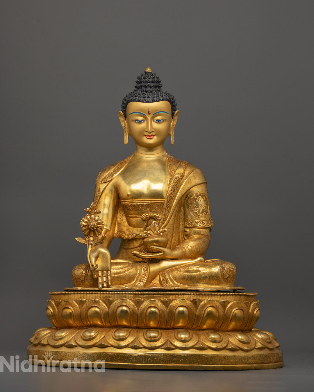 Medicine Buddha statue seated on lotus base holding healing herb