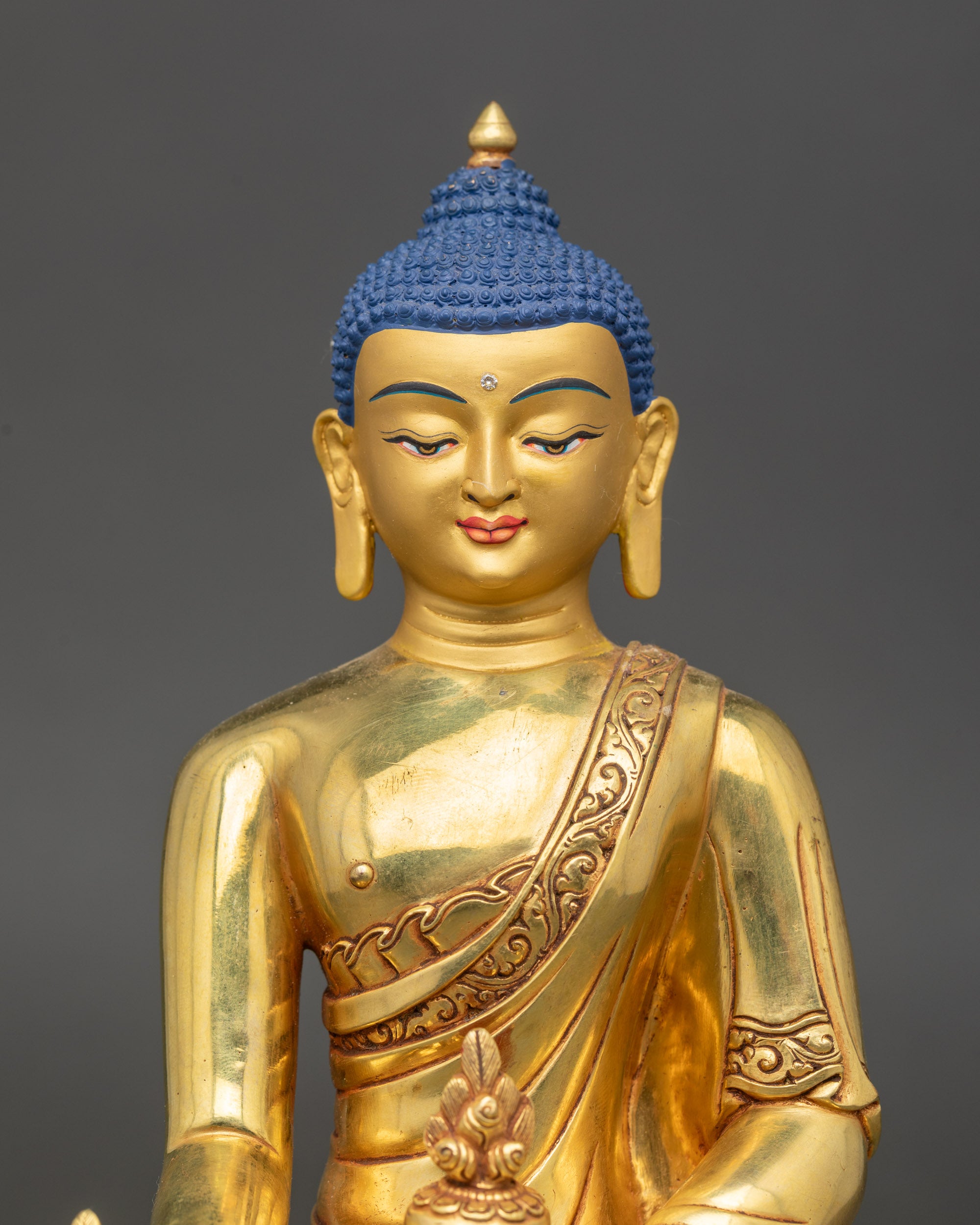 Close-up of gold-gilded Medicine Buddha holding amrita bowl and myrobalan stem