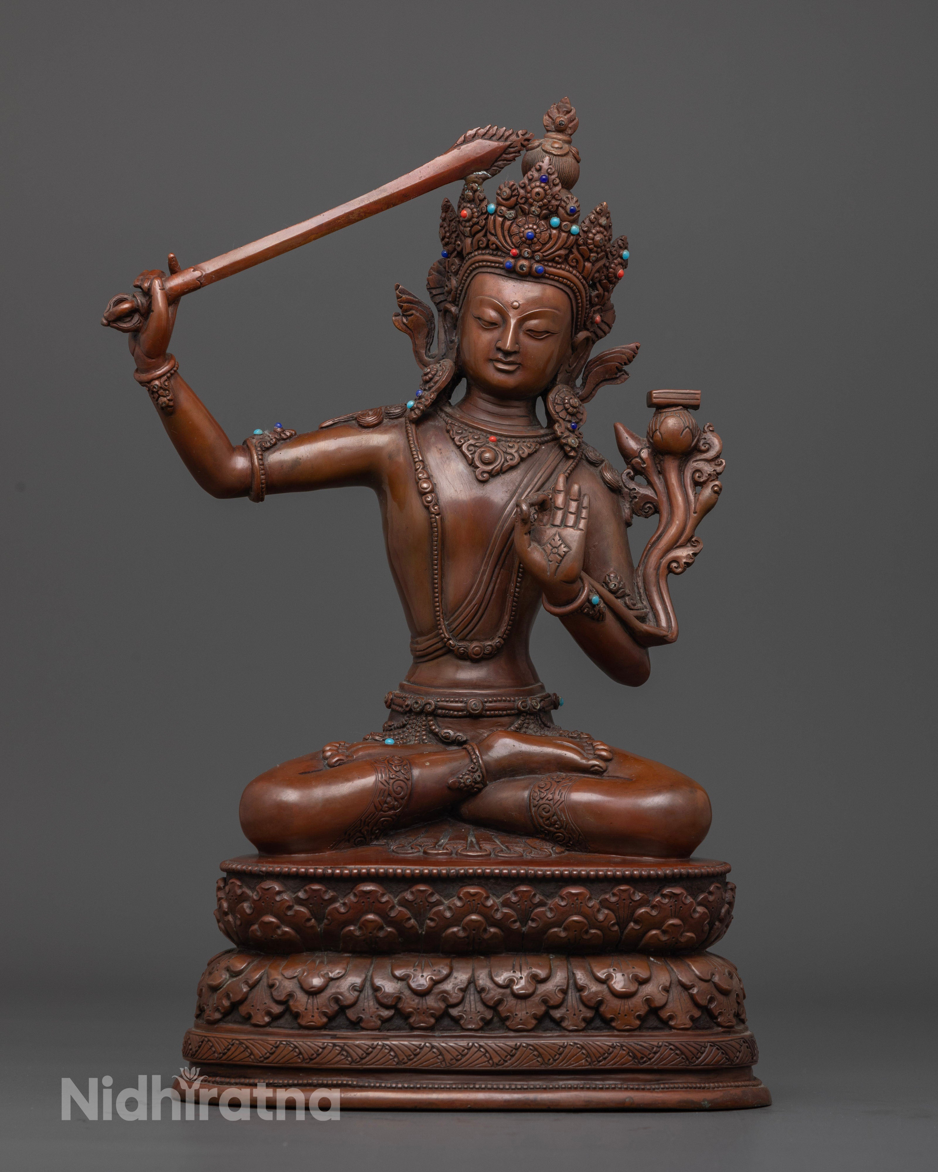 Oxidized Manjushri statue seated gracefully on a lotus throne, handcrafted with intricate detailing and adorned with semi-precious stones, symbolizing wisdom and enlightenment.
