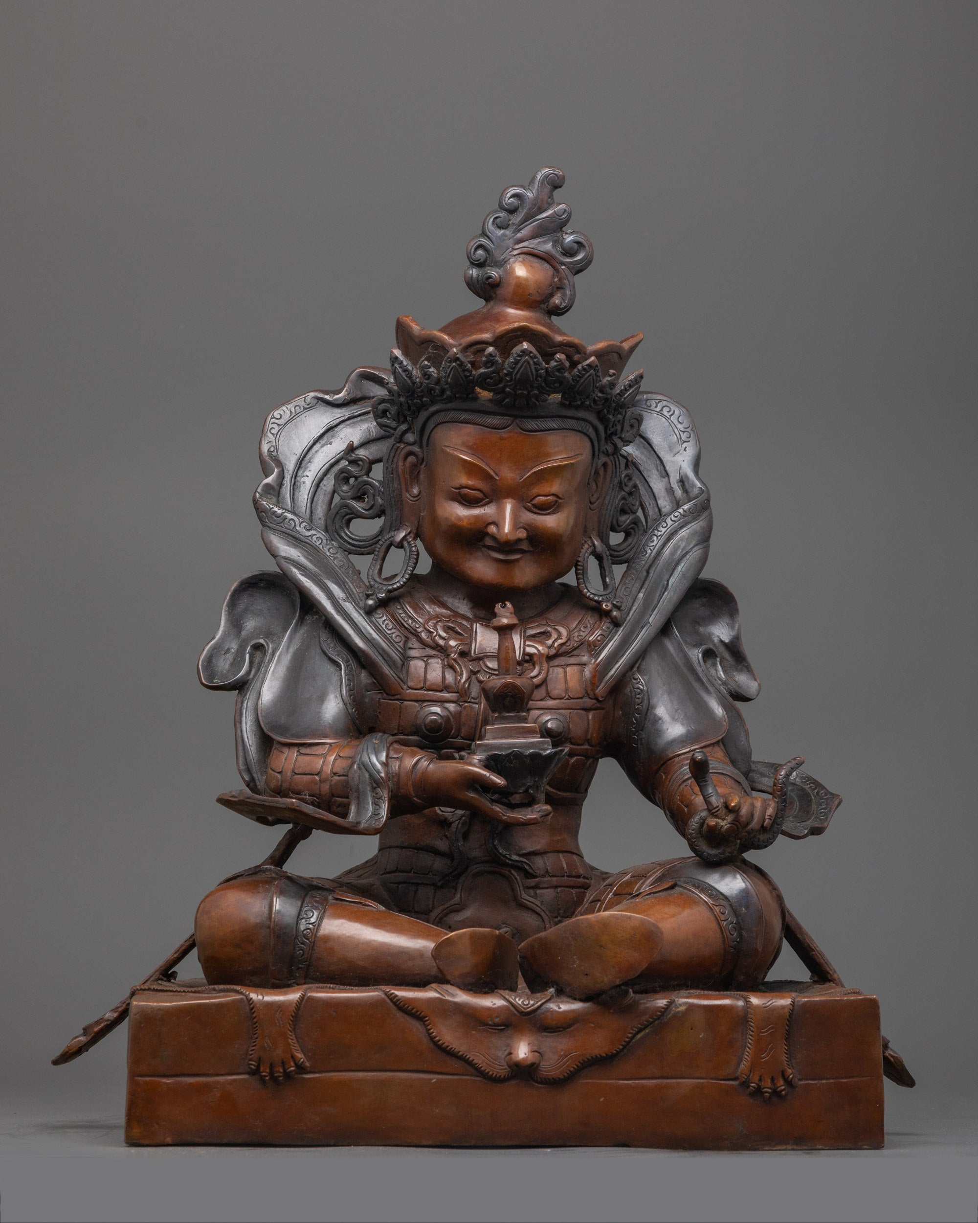 Oxidized copper Vaisravana statue seated in a regal posture, embodying the guardian