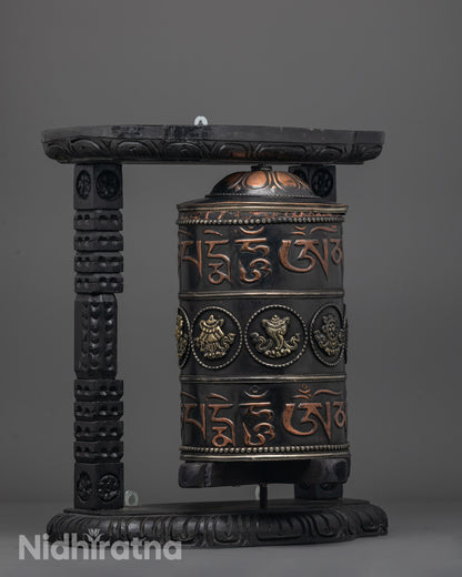 Prayer wheel showcasing bronze auspicious symbols and rich black acrylic paint finish