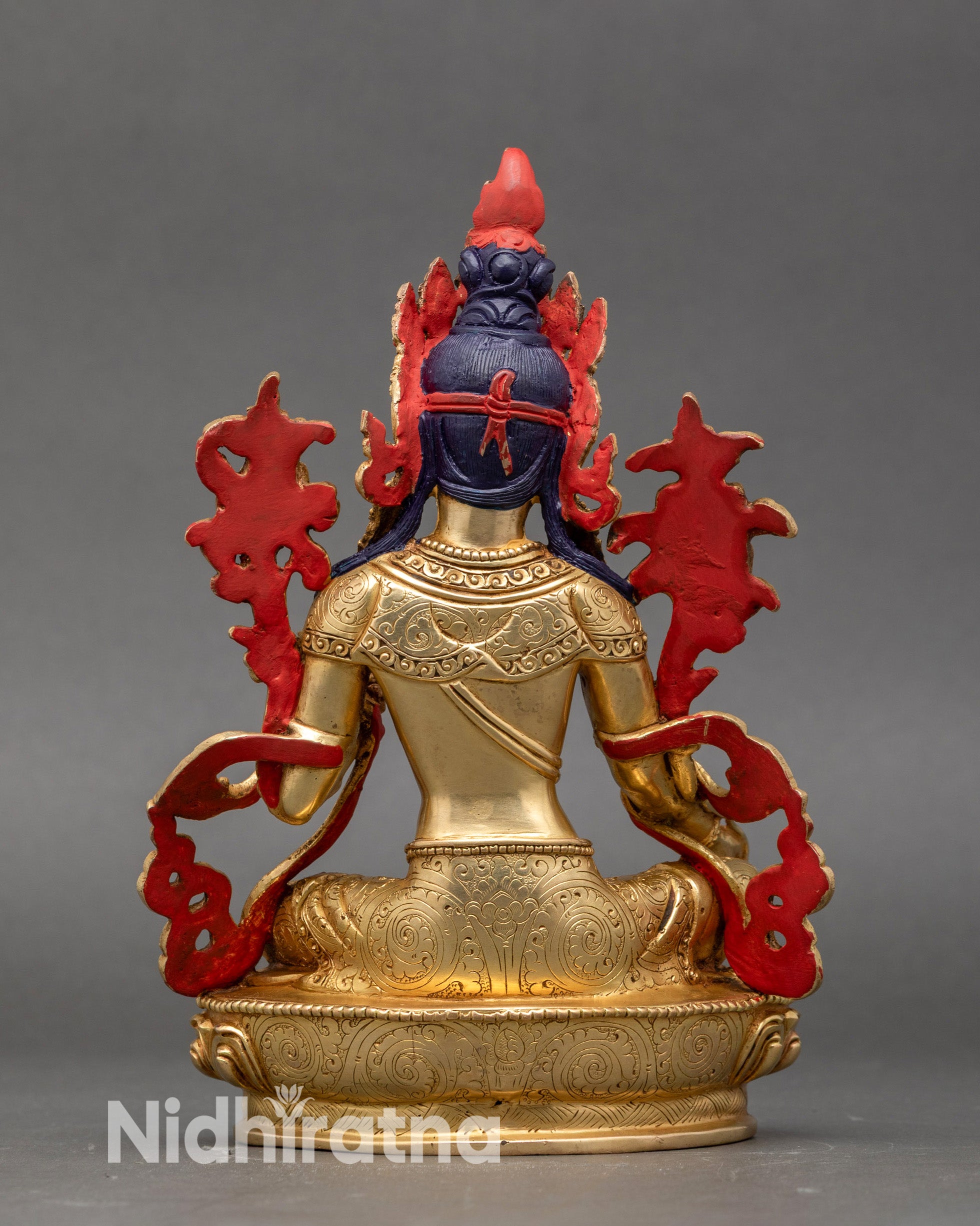 Rear view of gold fire-gilded Green Tara statue showing carved robes and lotus base