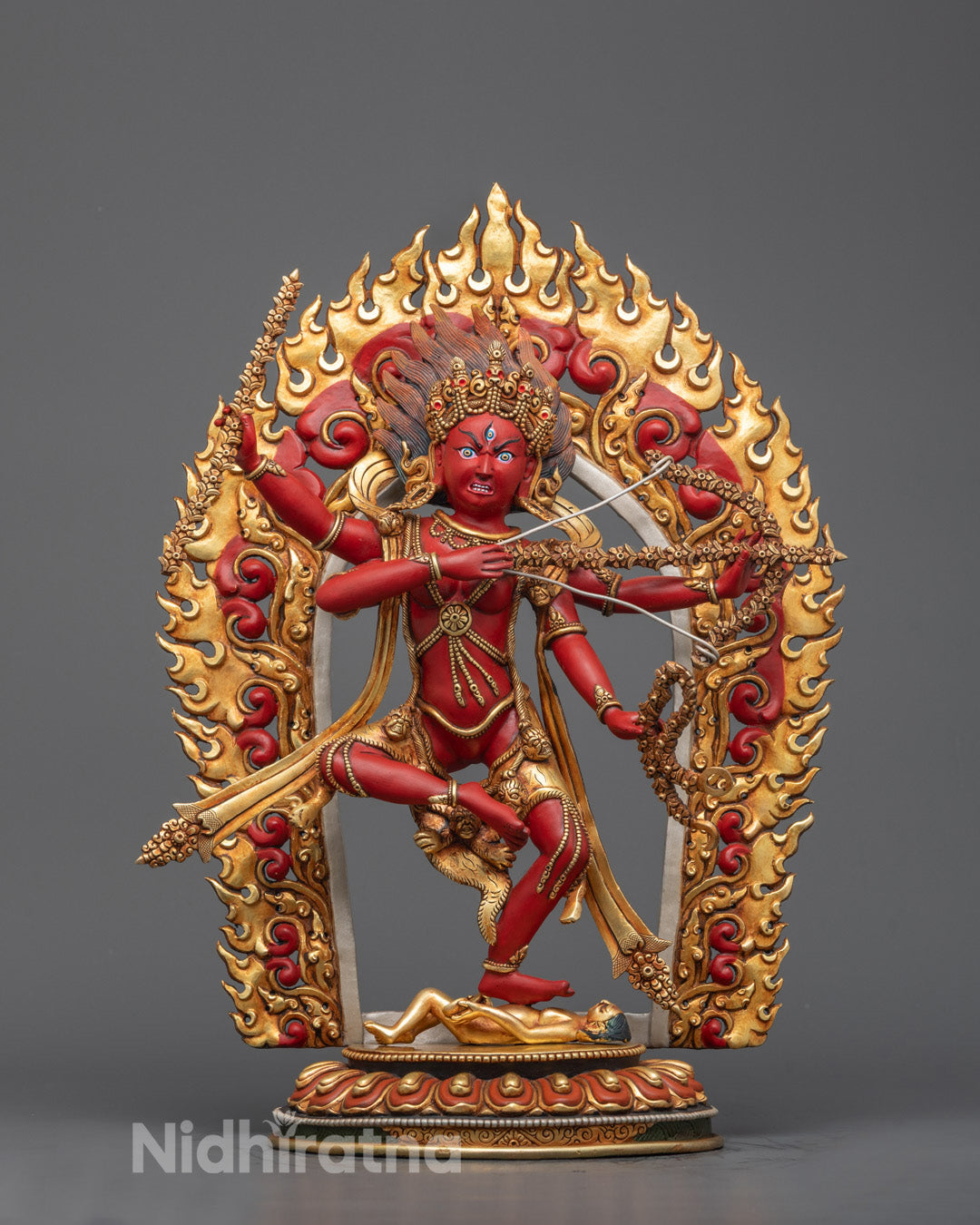 Front-view of Red Kurukulla statue with a bow and arrow, adorned with a golden flaming aureole