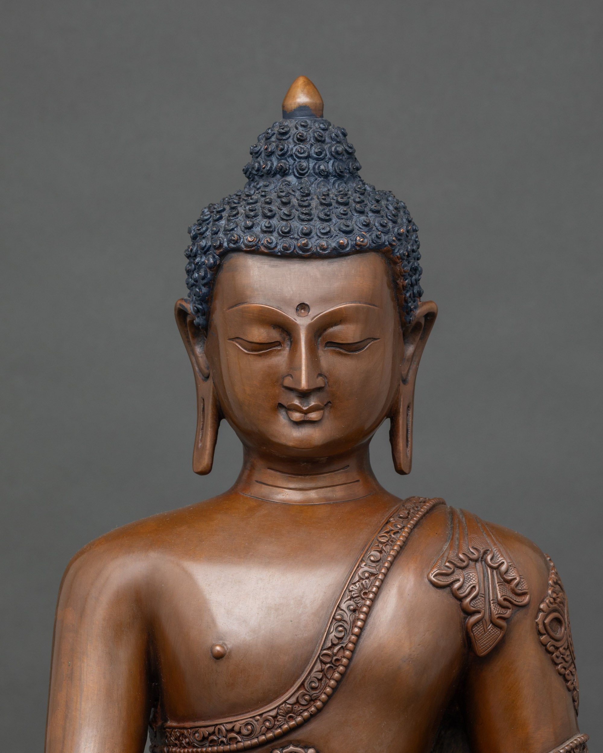 Regular close-up of Gautama Buddha statue showing intricate copper and oxidized patina