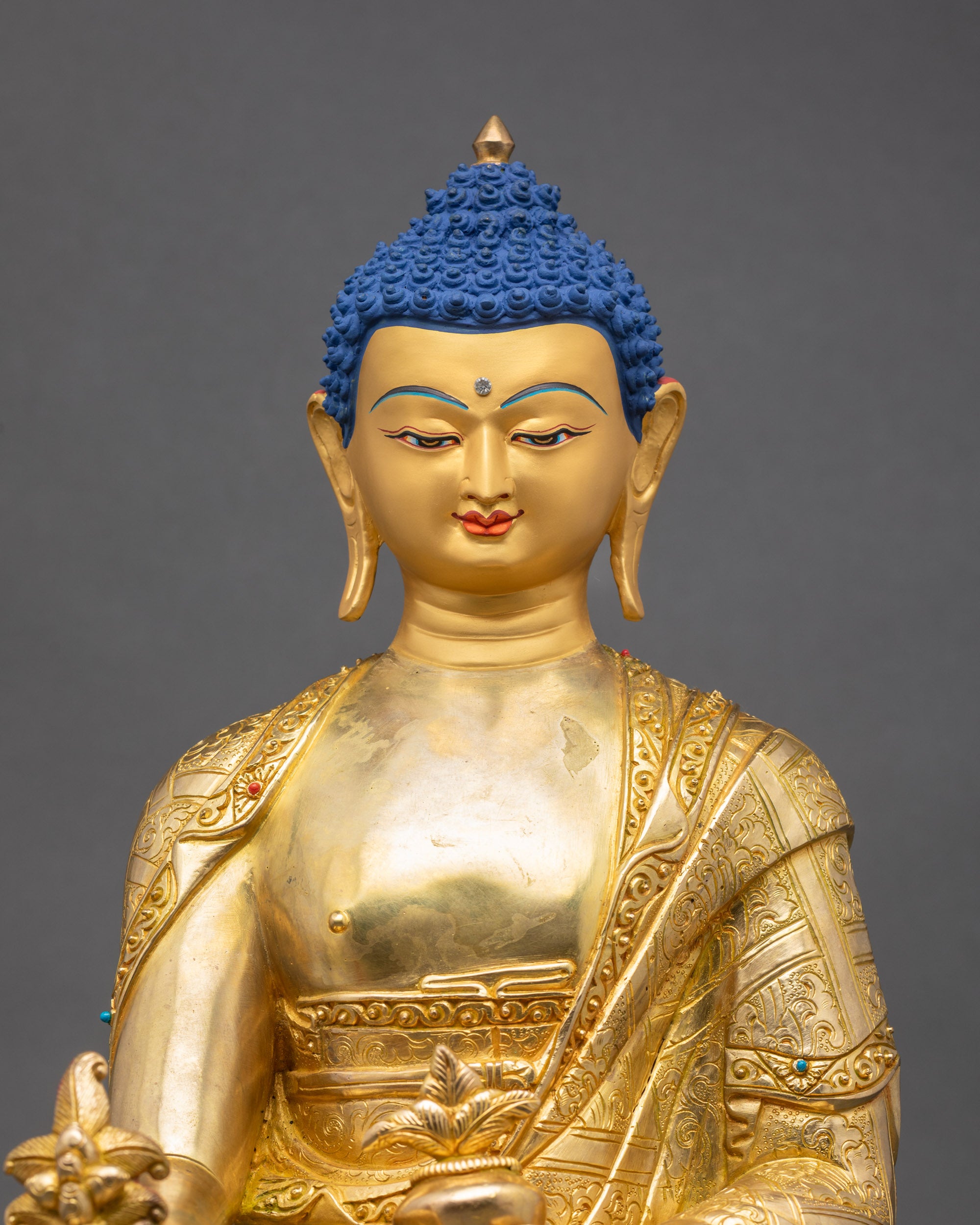 Regular close-up of Medicine Buddha, showing serene gold-painted face and intricate robes