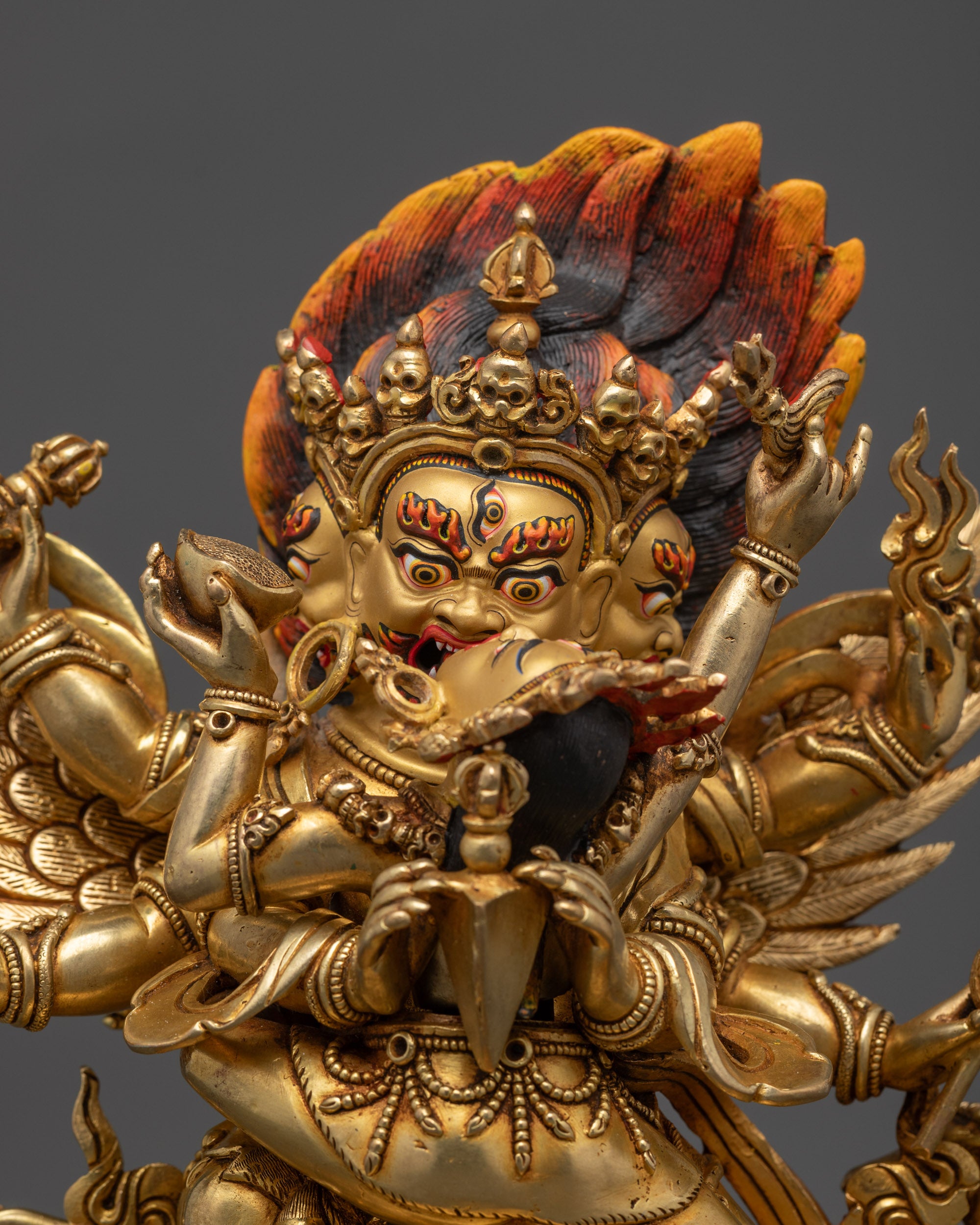 Regular close up Vajrakilaya deity showing three gold-gilded faces and ritual objects

