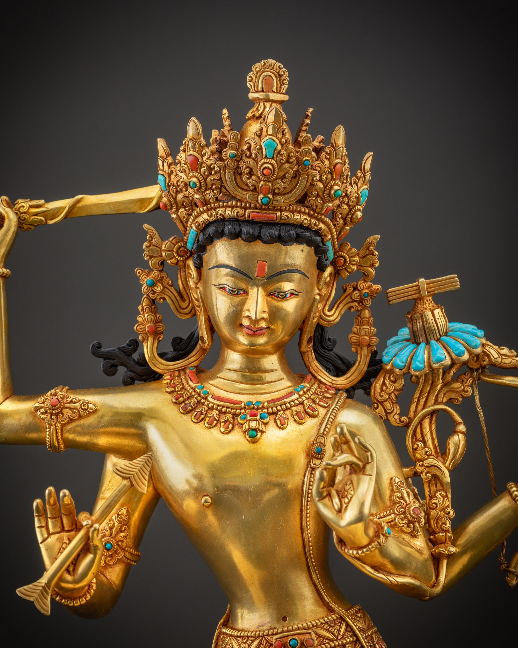 Regular close up face of Maha Manjushri statue with semi-precious stones and golden glow.

