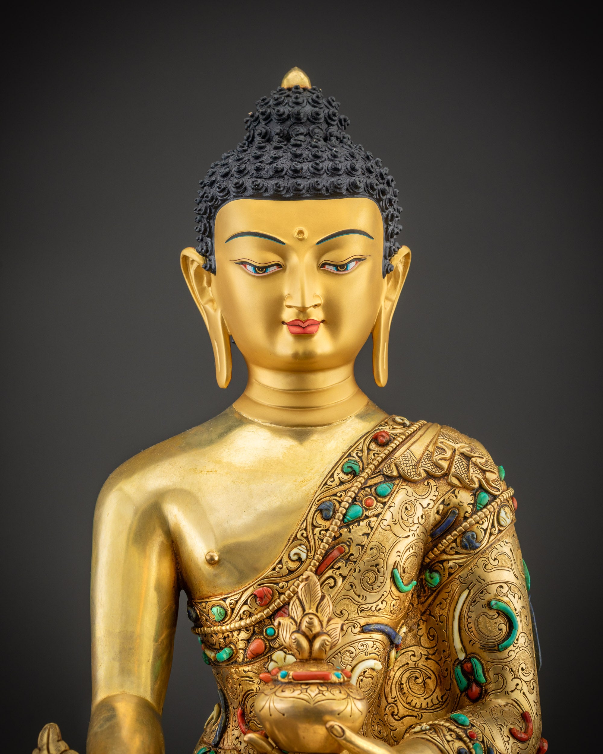 Regular close up face of Medicine Buddha highlighting gold-gilded face and semi-precious stones