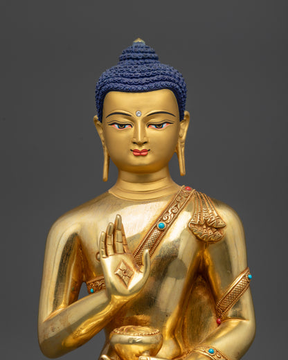 Regular close up of Amoghasiddhi Buddha statue showing gold-gilded face and serene expression
