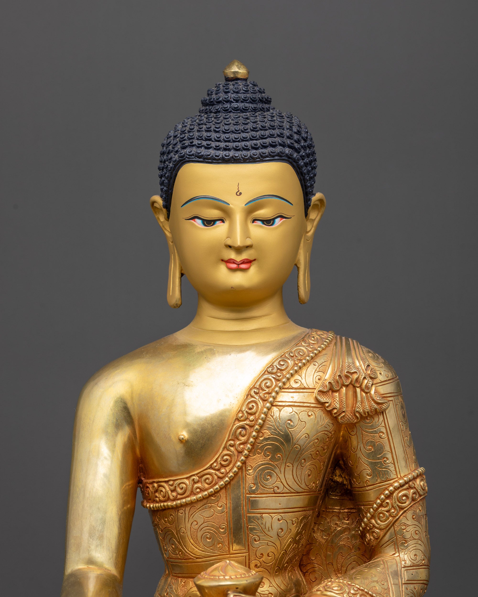 Regular close up of Buddha statue showing gold-gilded face and intricate monk’s robe
