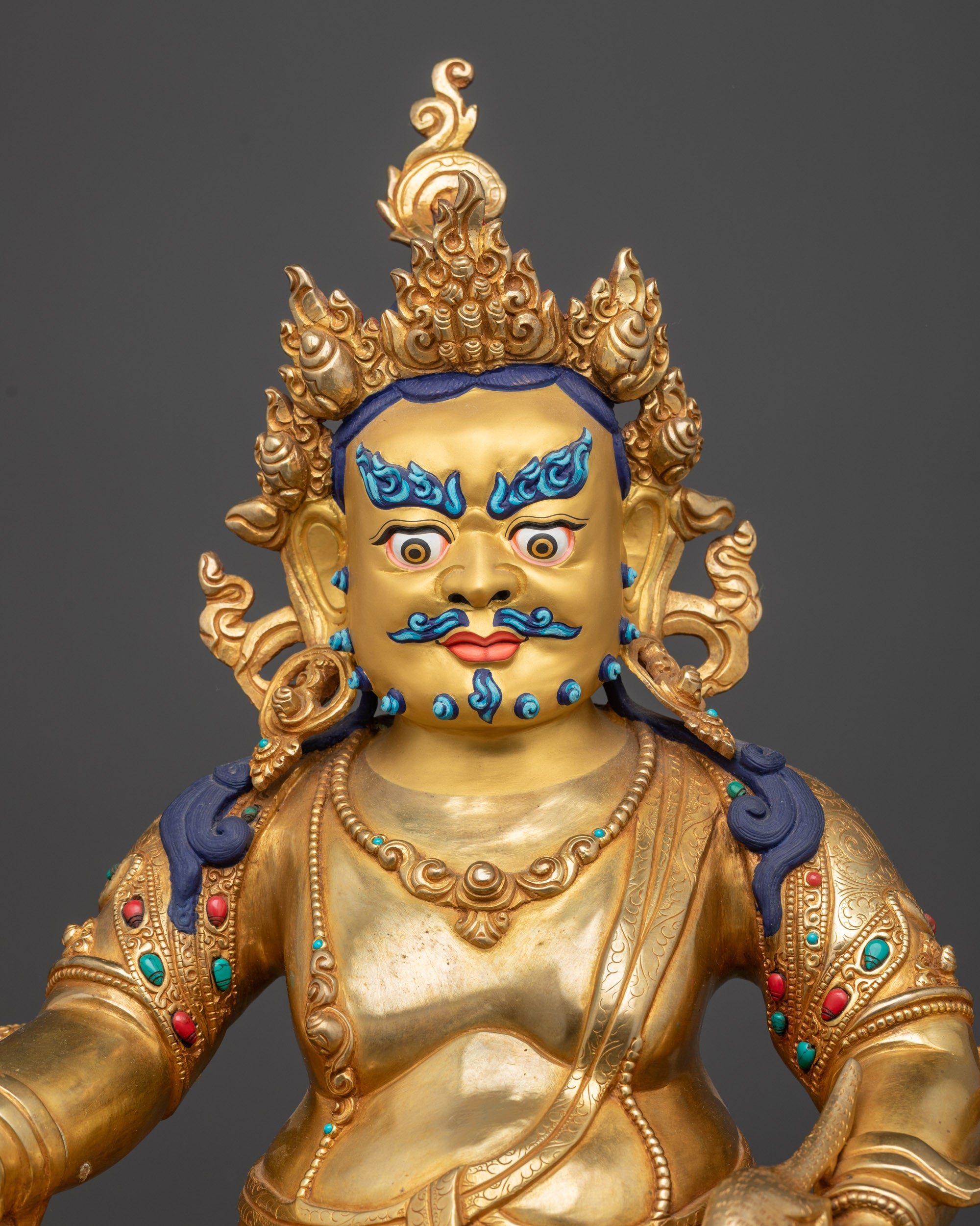 Regular close up of Dzambhala Statue showing gold fire-gilded body and semi-precious stones
