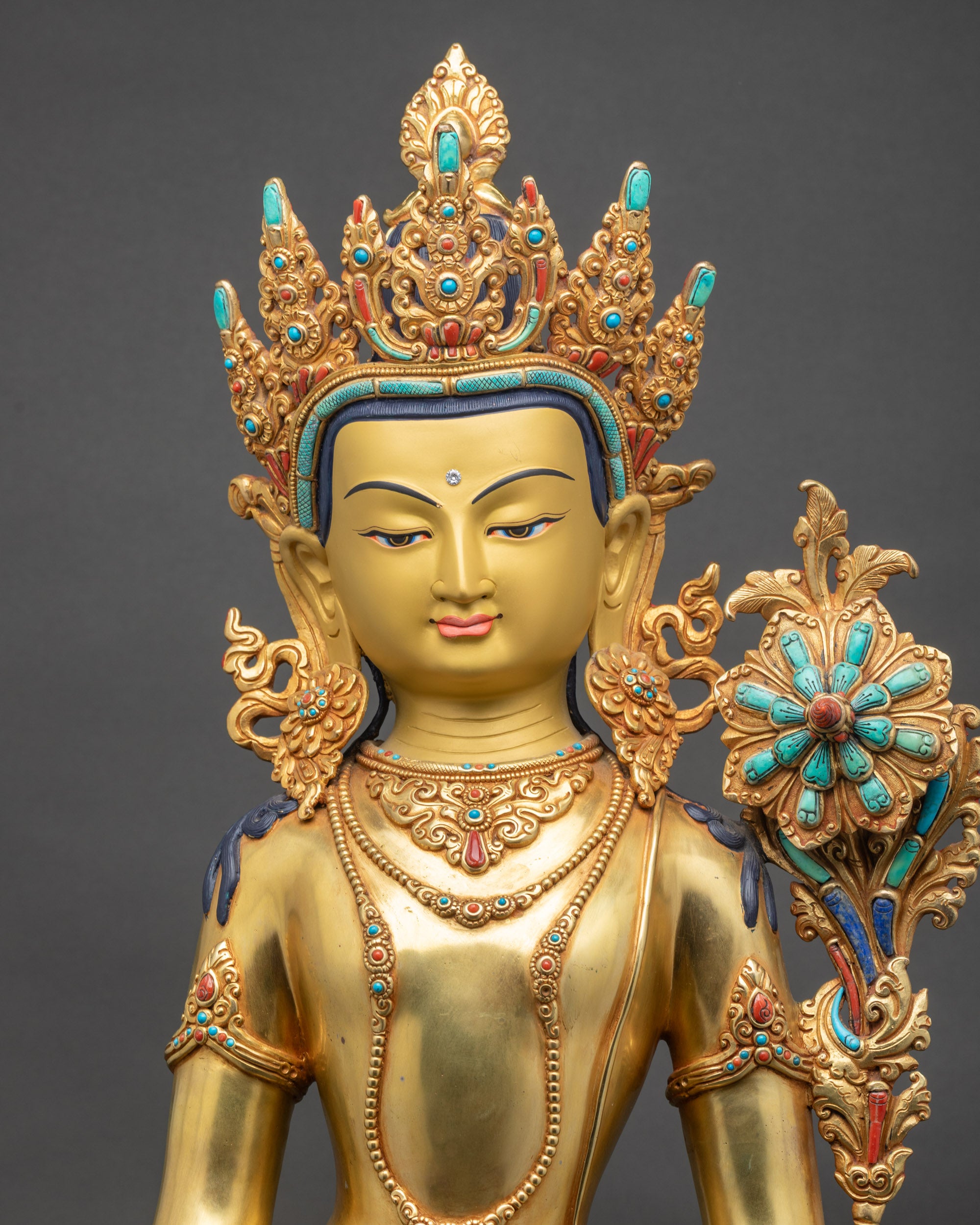 Regular close up of Padmapani Bodhisattva statue showing serene gold-gilded face